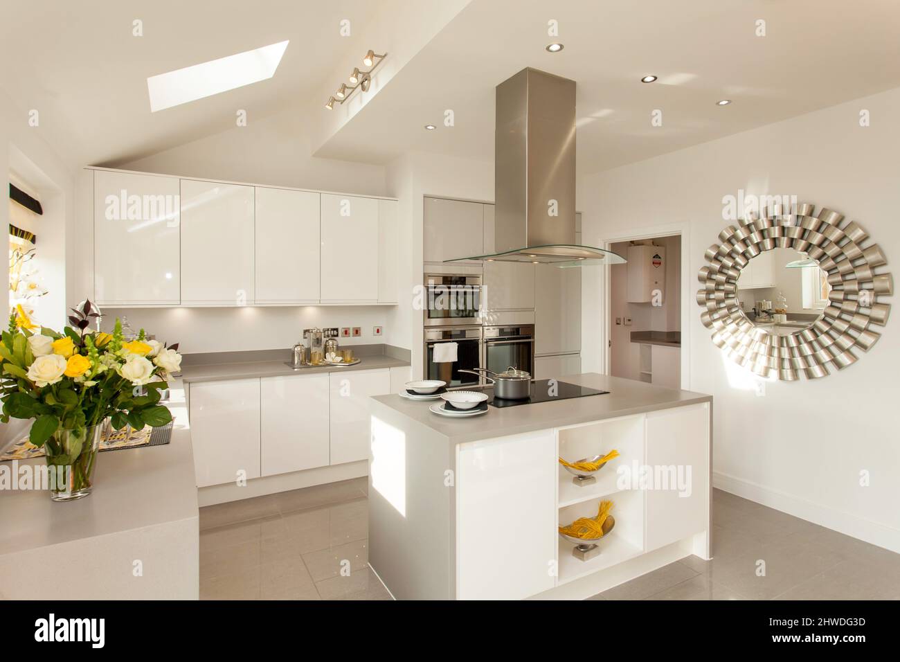 Kitchen with centre island cooking area, induction hob and cooker hood in modern showhome. Stock Photo