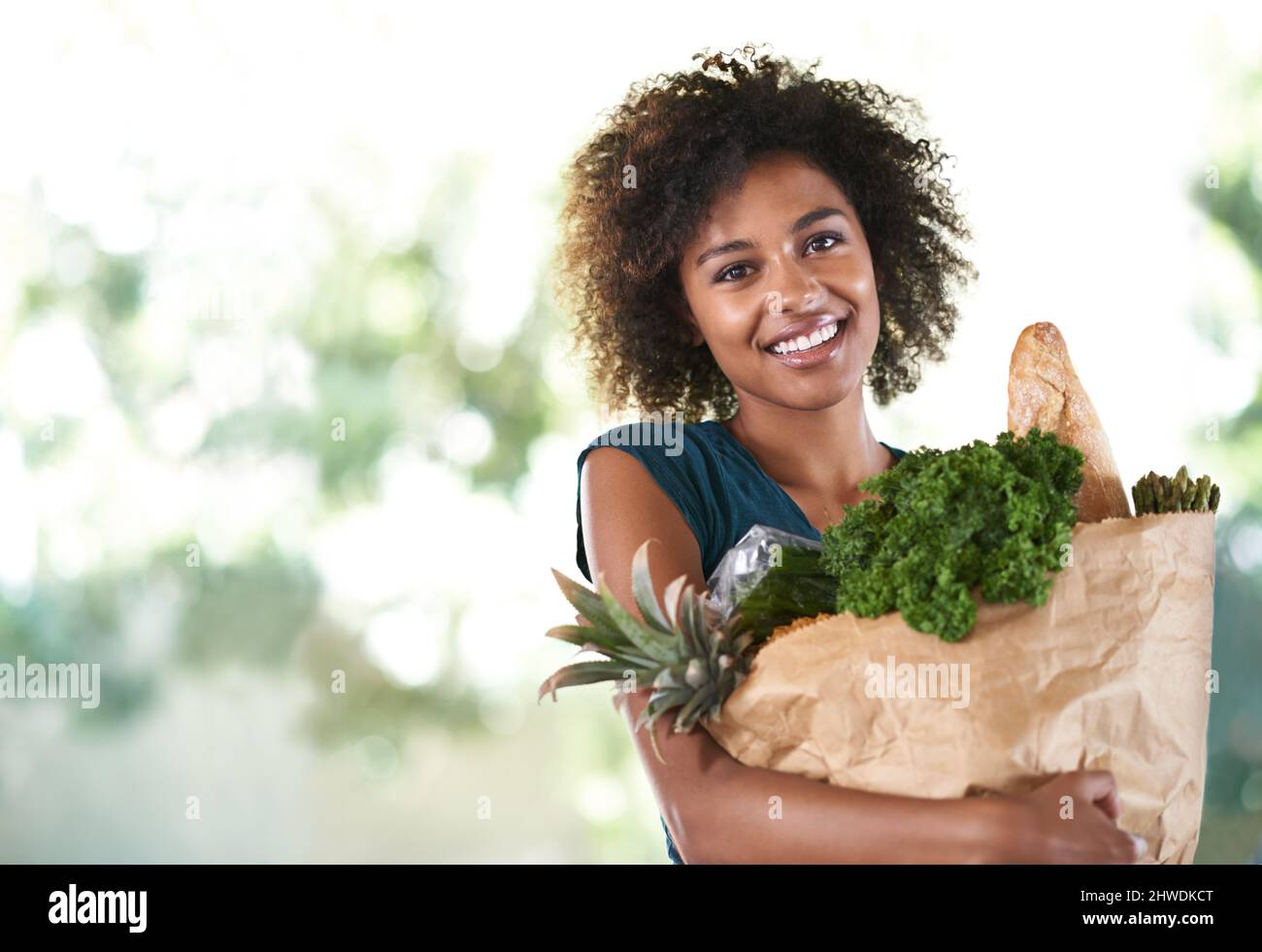 Bag of health. Young girl smiling while holding her groceries - isolated. Stock Photo