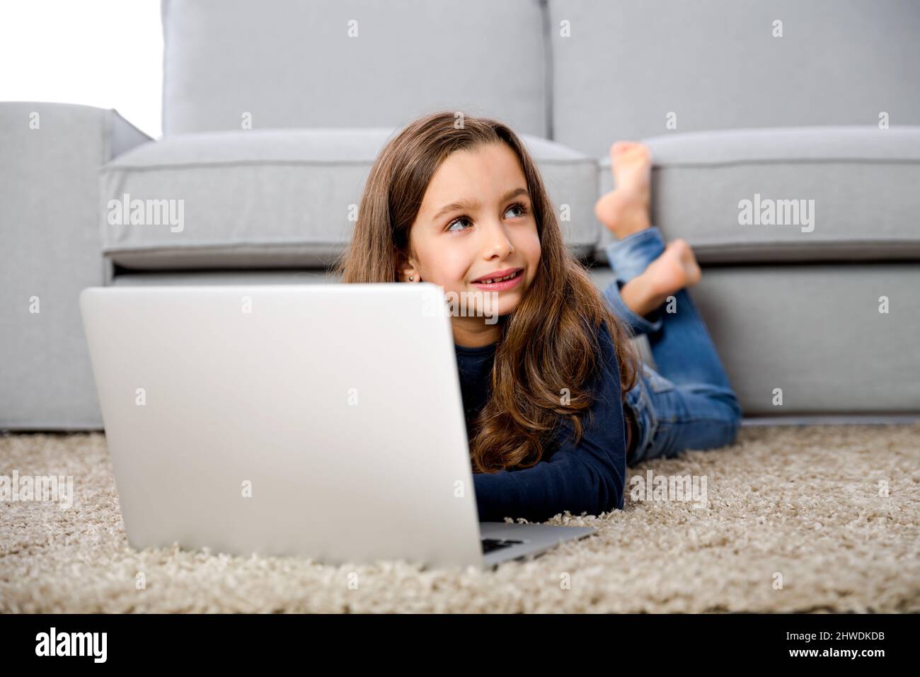 Happy little girl at home working with a laptop Stock Photo - Alamy