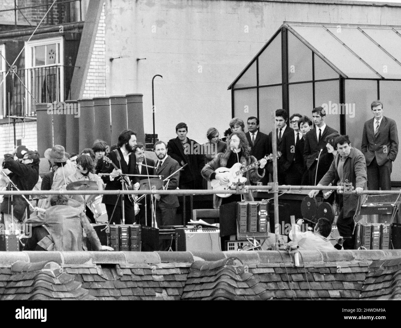 The Beatles perform a rooftop concert at Apple Headquarters, 3 Saville Row London on 30th January 1969. The performance was a part of filming for a documentary of the band rehearsing and recording the album Let It Be. The 42 minute session drew crowds to the street & adjoining rooftops. This was the band's final live performance before breaking up in April 1970. Performing on the roftop left to right: Ringo Starr, Paul McCartney, John Lennon and George Harrison. Stock Photo