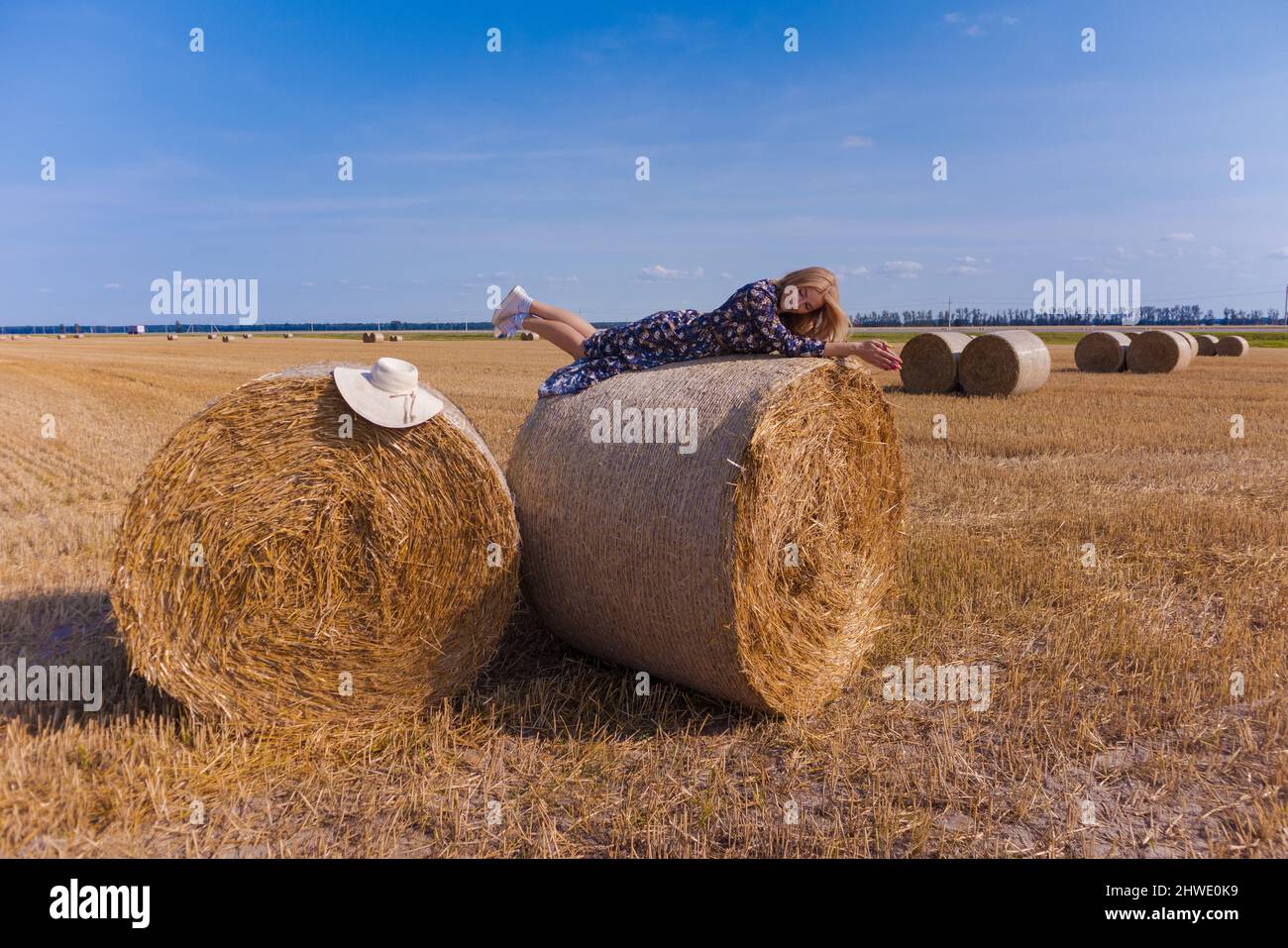 A blonde girl with long hair in a white hat is resting and posing near ...