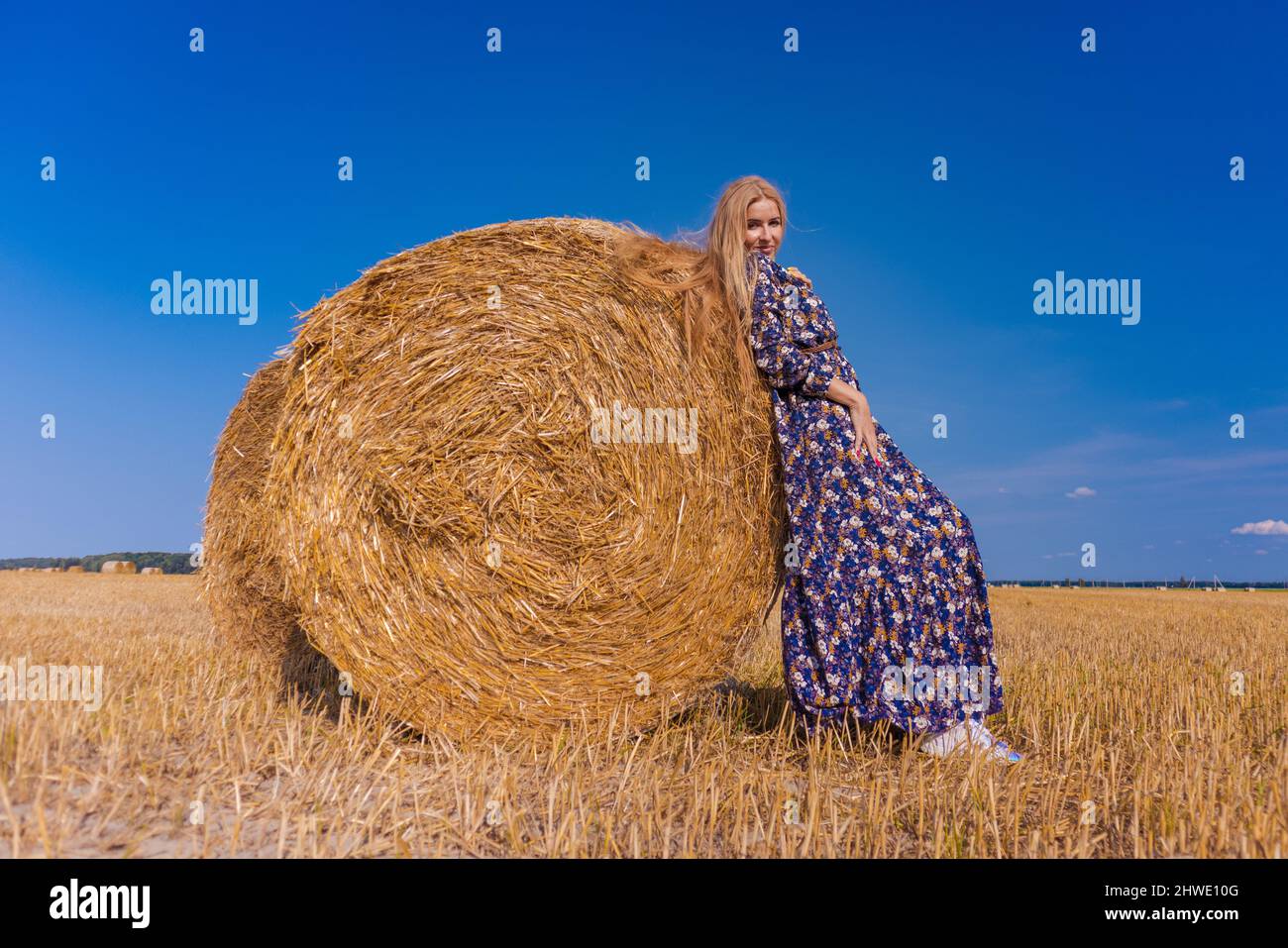 A blonde girl with long hair in a white hat is resting and posing near ...