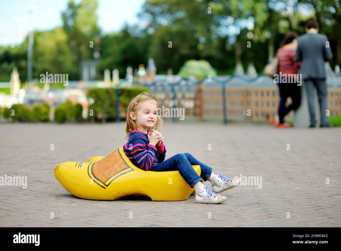 Little girl playing with traditional Dutch wooden boot called klomp at Madurodam miniature park, The Hague, Netherlands, Holland. Stock Photo