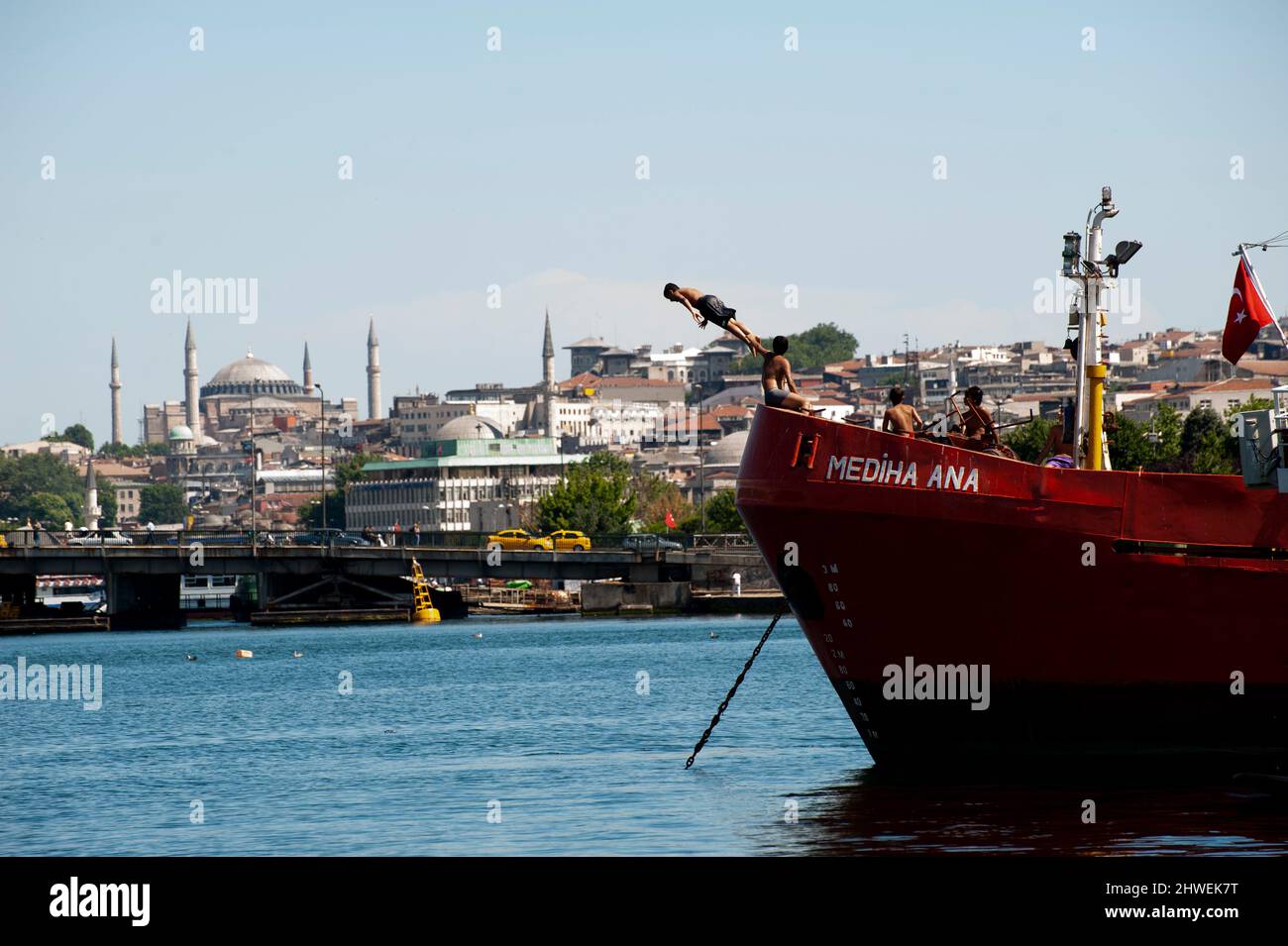 Young Turkish boy jumps off a boat into the harbor sea across from the Hagia Sophia Mosque in Istanbul, Turkey. Stock Photo