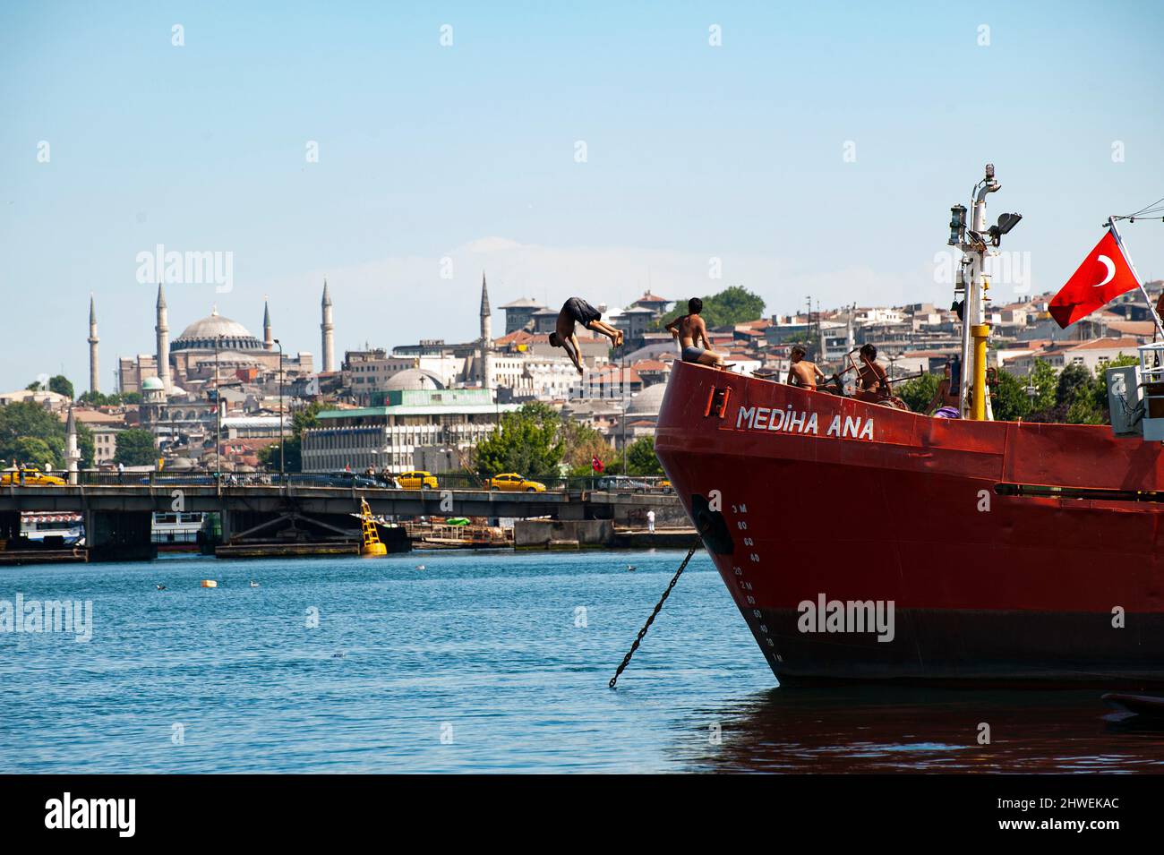 Young Turkish boy jumps off a boat mamed Mediha Ana into the harbor sea across from the Hagia Sophia Mosque in Istanbul, Turkey. Stock Photo