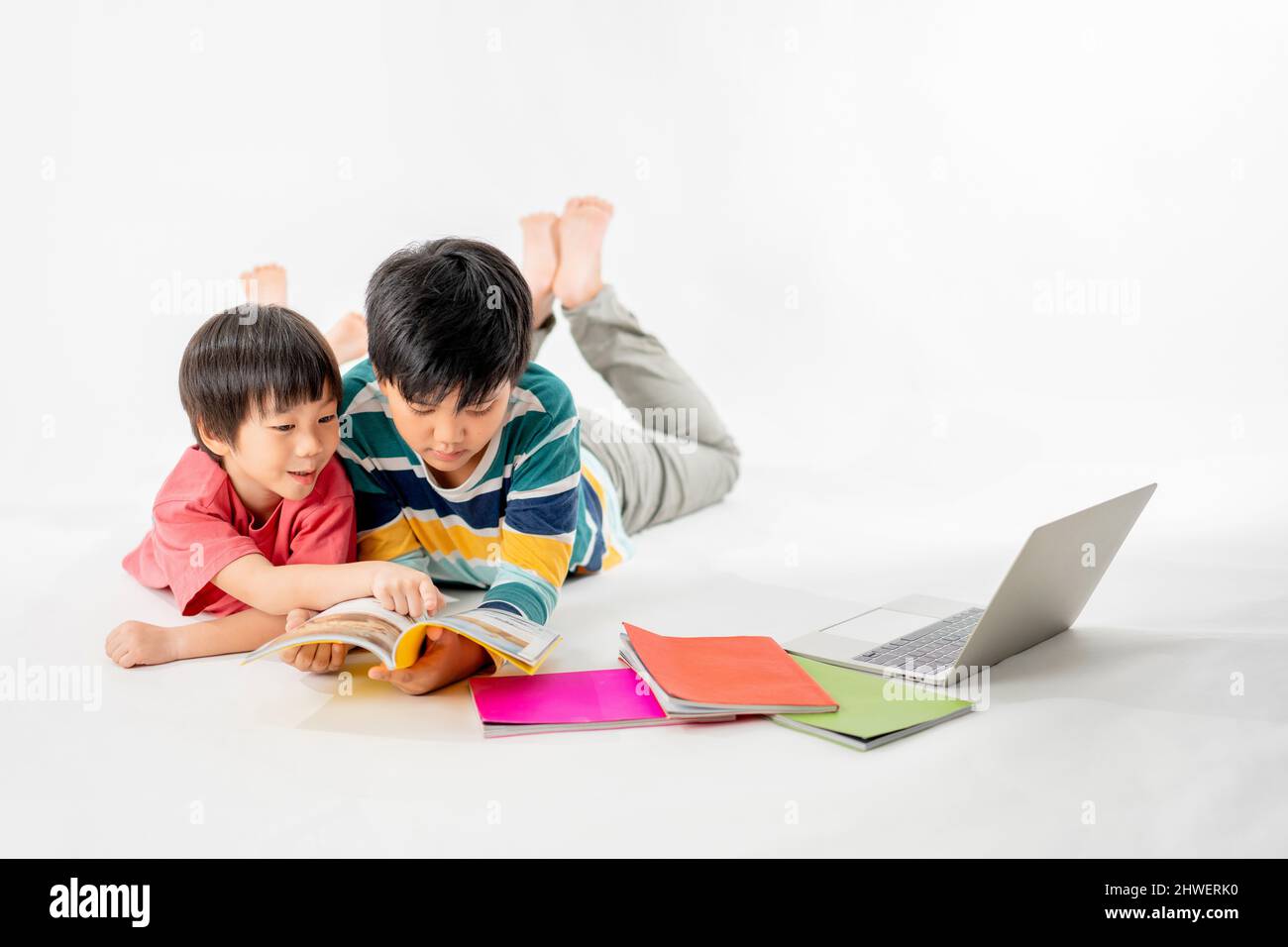 Portrait of Happy asian boys, Brother on floor with laptop and books ...