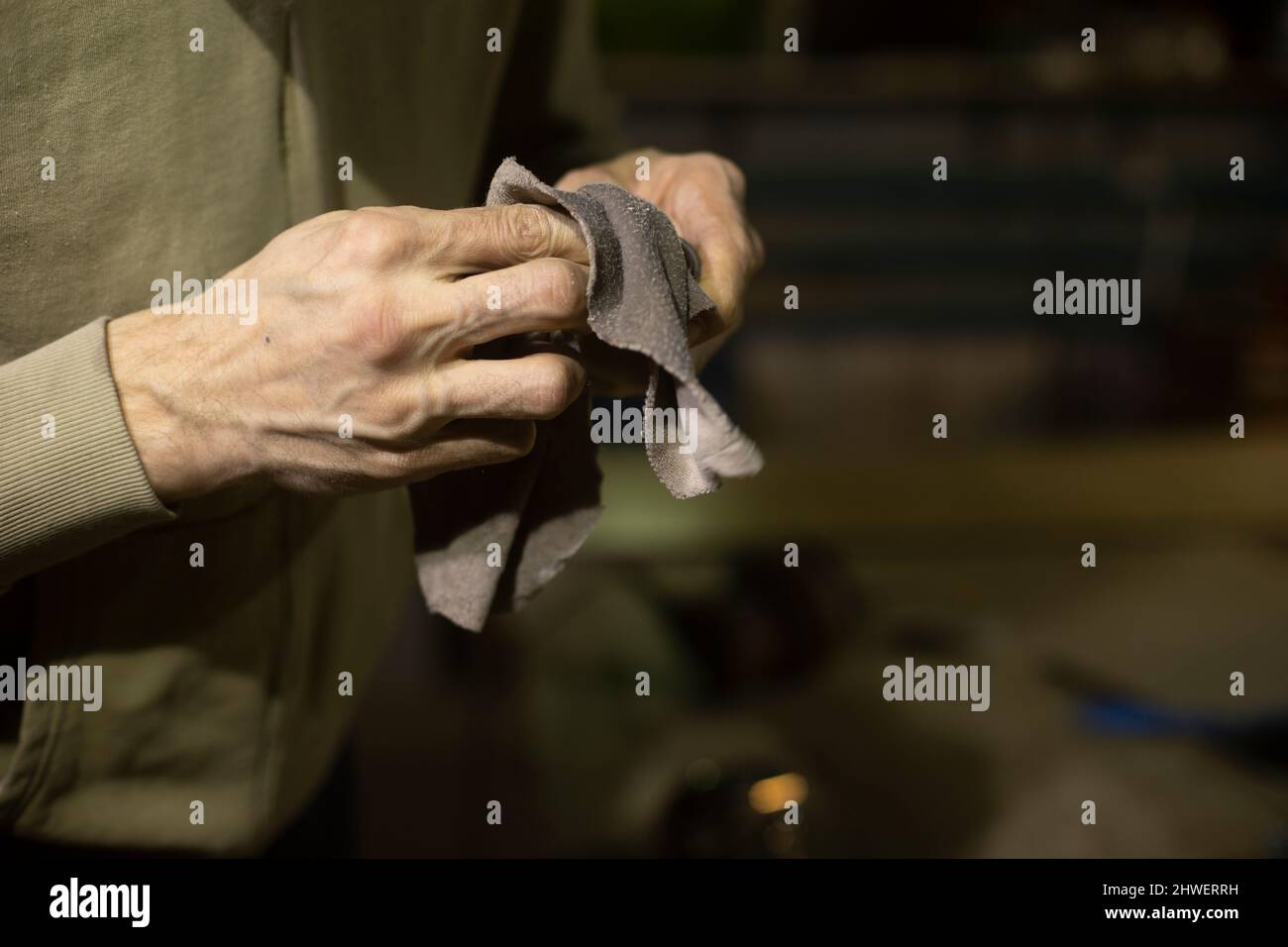 Wipe part with rag. Rag in his hands. Person cleans mechanism from dirt