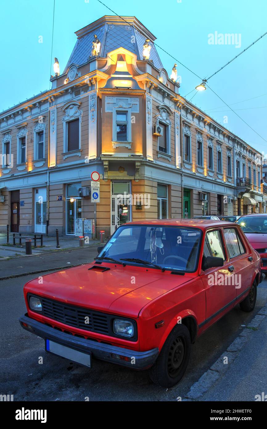 A beautifully preserved legendary Yugo parked in front of historical buildings in Zemun, Belgrade, Serbia at twilight. Stock Photo
