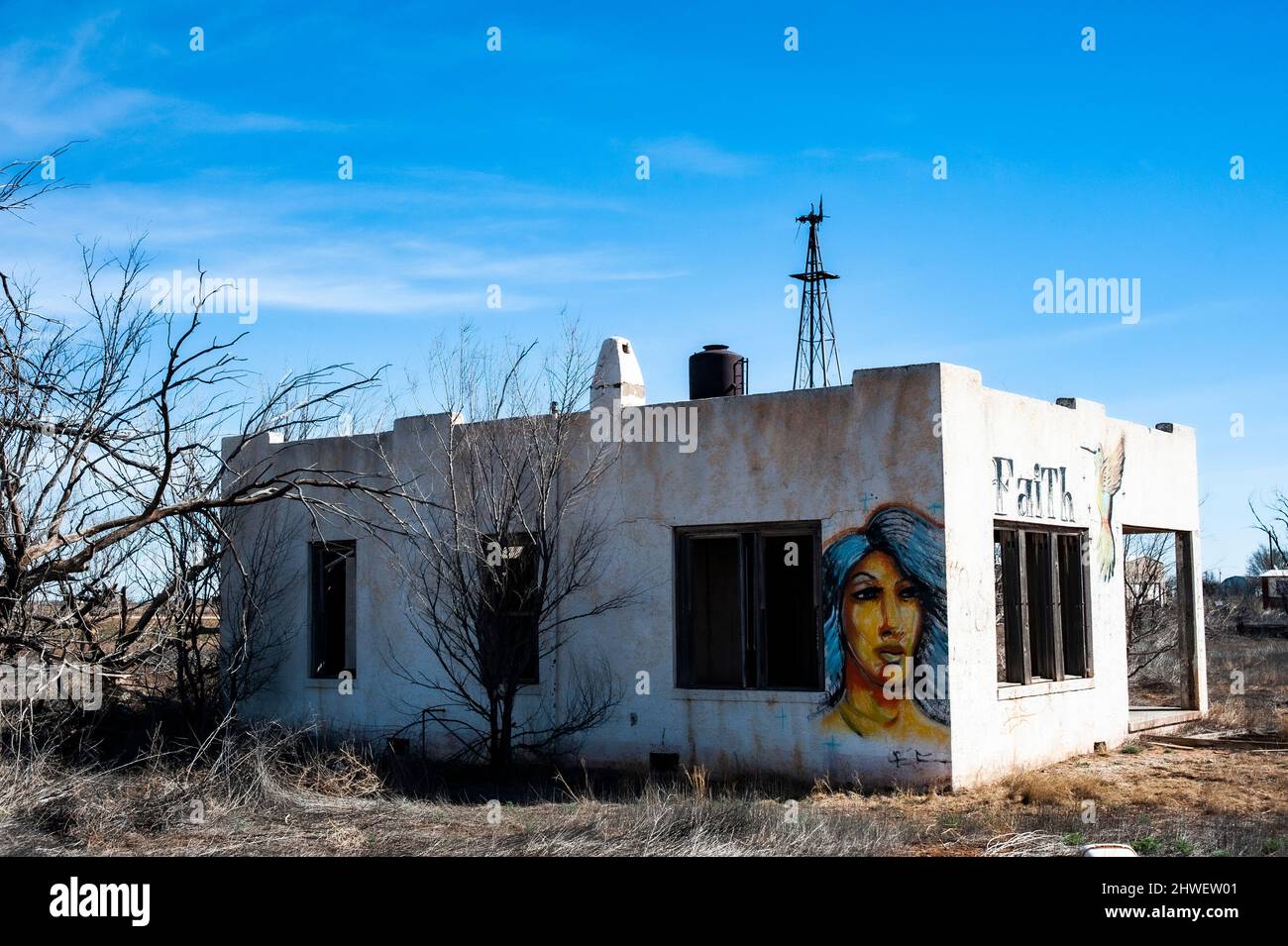 Mural of woman's face on an abandoned empty house with lots of land in a rural part of the state of New Mexico. Stock Photo