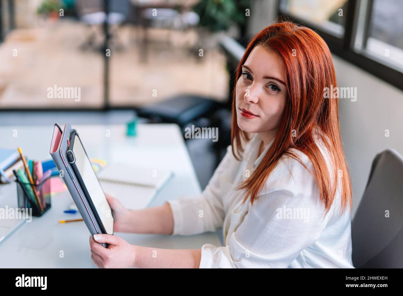 Young woman looking at camera while using tablet at work Stock Photo