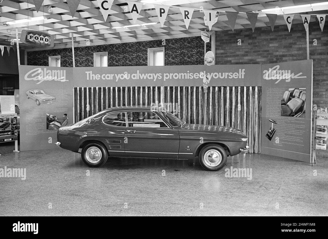 The launch of The Ford Capri Mk1.Picture taken at a showroom of car dealer Dennis J Hands in the Reading area, and shows the new Ford Capri on the forecourt, and the promotion ladies enjoying the day.  The Ford slogan, used as part of the promotion was, 'the car you have always promised yourself'  The first Ford Capri was introduced in January 1969 at the Brussels Motor Show, with sales starting the following month. The intention was to reproduce in Europe the success Ford had had with the North American Ford Mustang; to produce a European pony car  Picture taken 14th February 1969The launch o Stock Photo