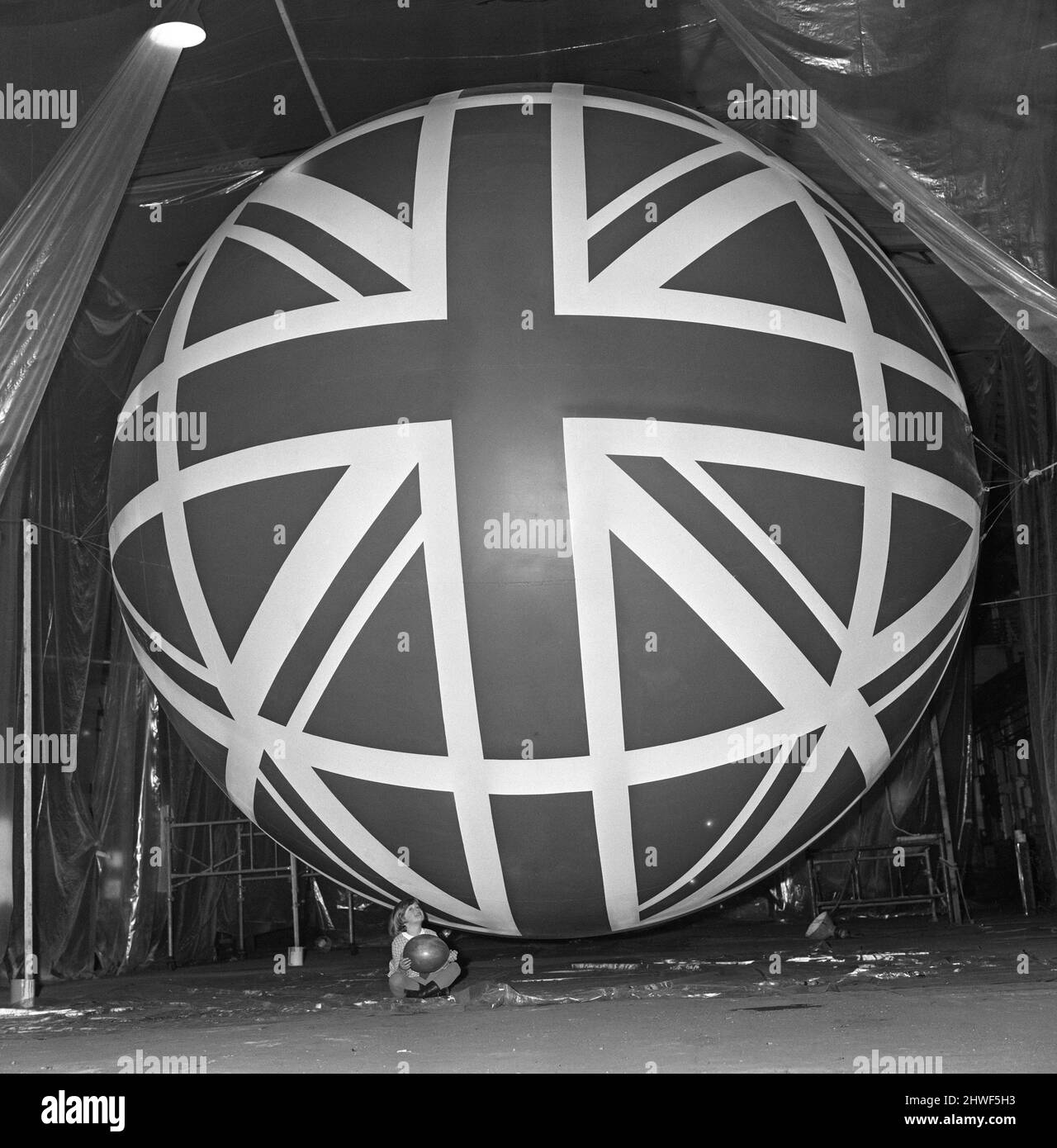 Union Jack Giant Balloon at Expo 70 Little Miss Susan Howlett, five, is dwarfed by the huge balloon destined to fly over the British pavilion at the Expo 70.   The exhibition will open at Osaka, Japan in March 1970.  The balloon is 20 feet in diameter  Lynne is employed by Loyne Limited, of Ashton under Lyne, Lancashire, where the balloons are being given a special flexible type of coating.  Picture taken 31st December 1969 Stock Photo