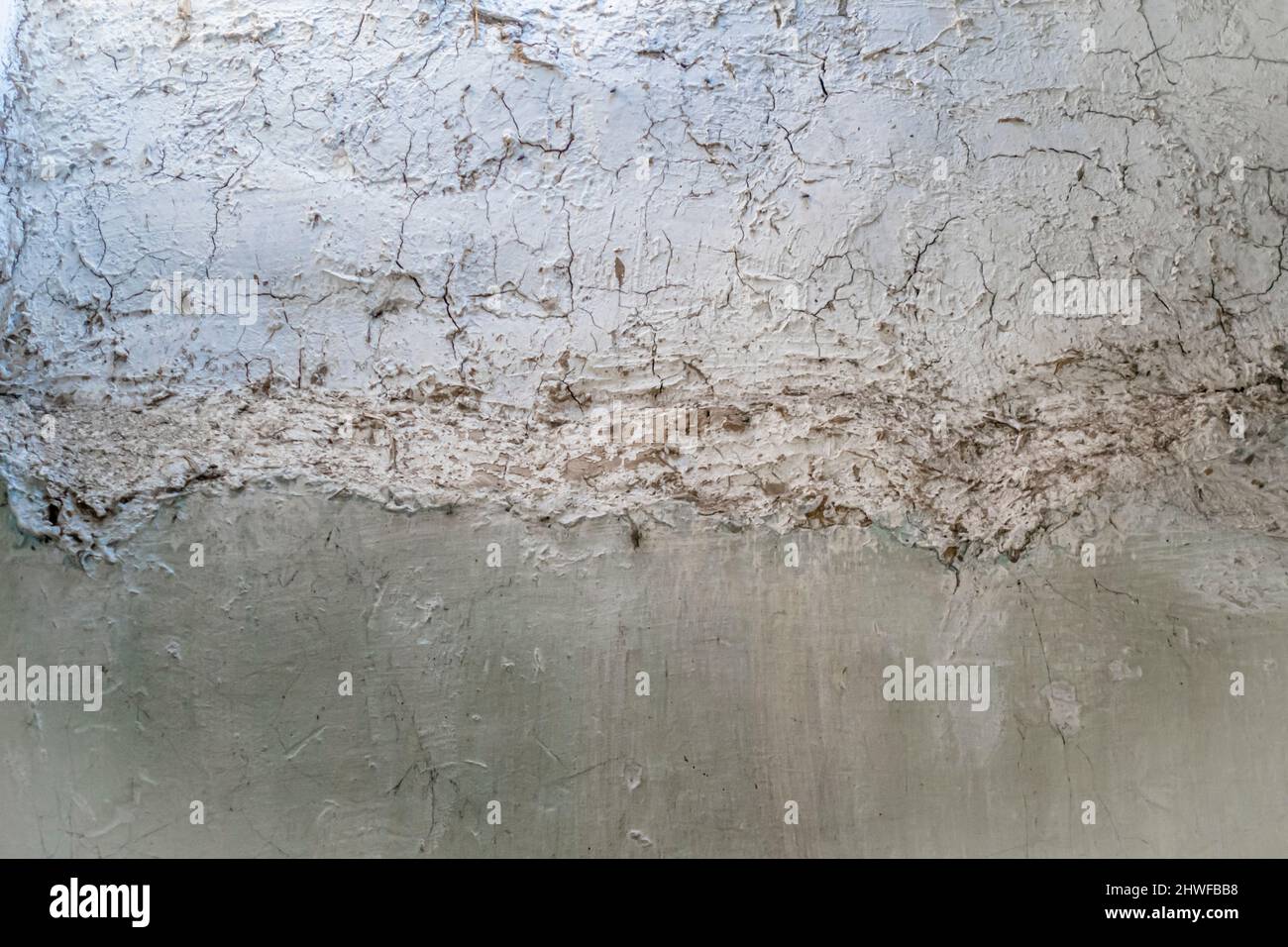 Pale paintwork cracked on an old concrete wall with paint weathered Stock Photo