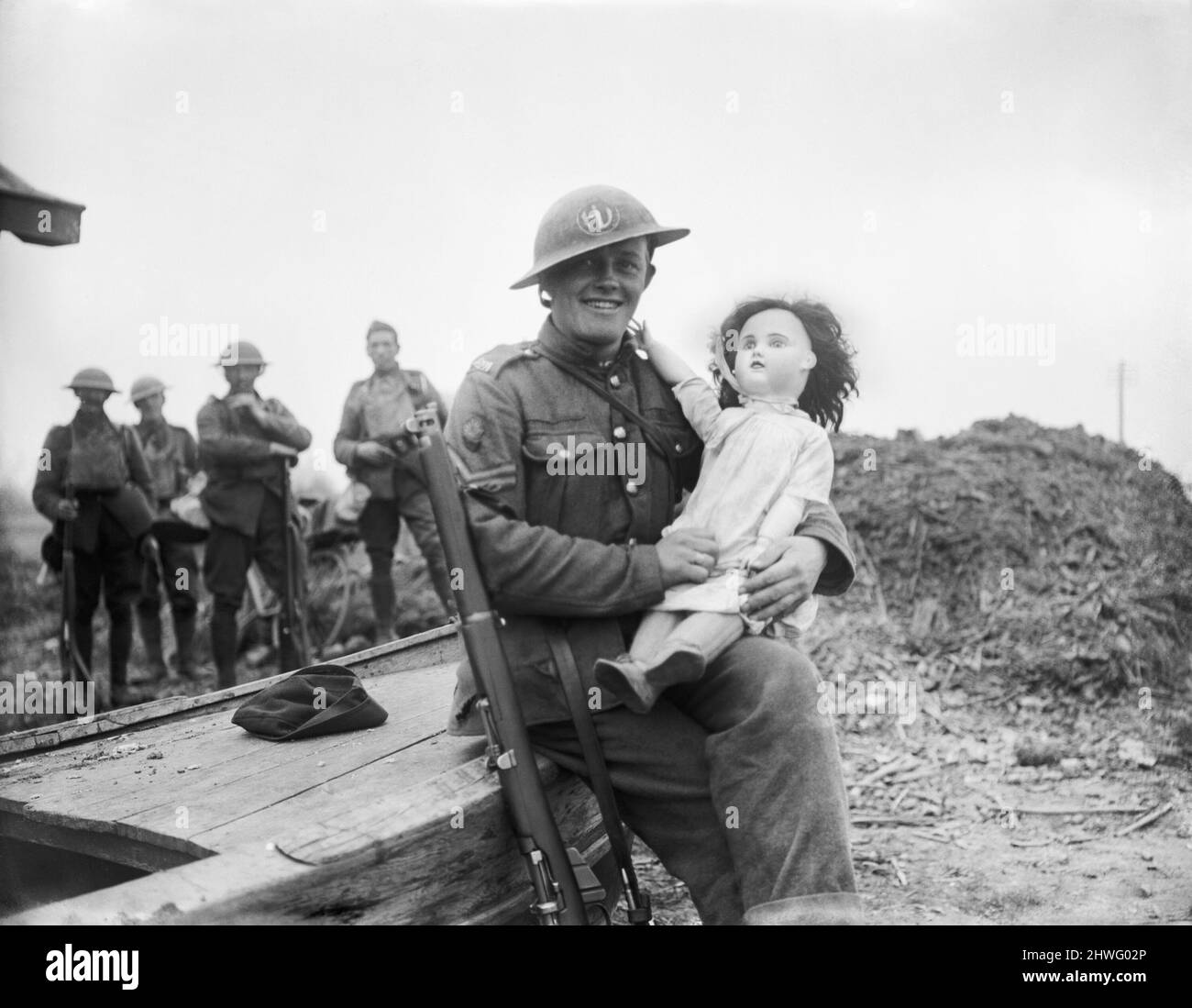 A soldier holding a doll found in the ruins of a village on the Western Front during WW1 Stock Photo