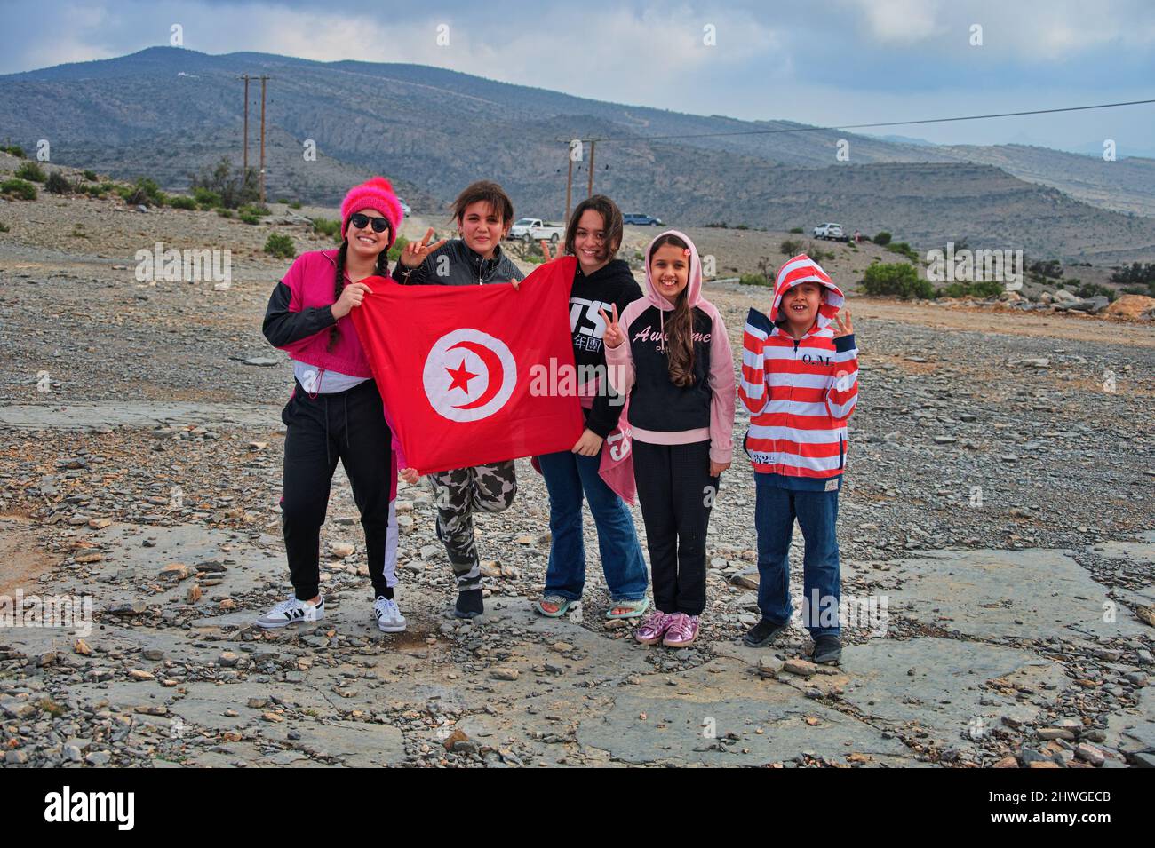 Group of girls traveling in Oman holding a flag of Tunisia Stock Photo