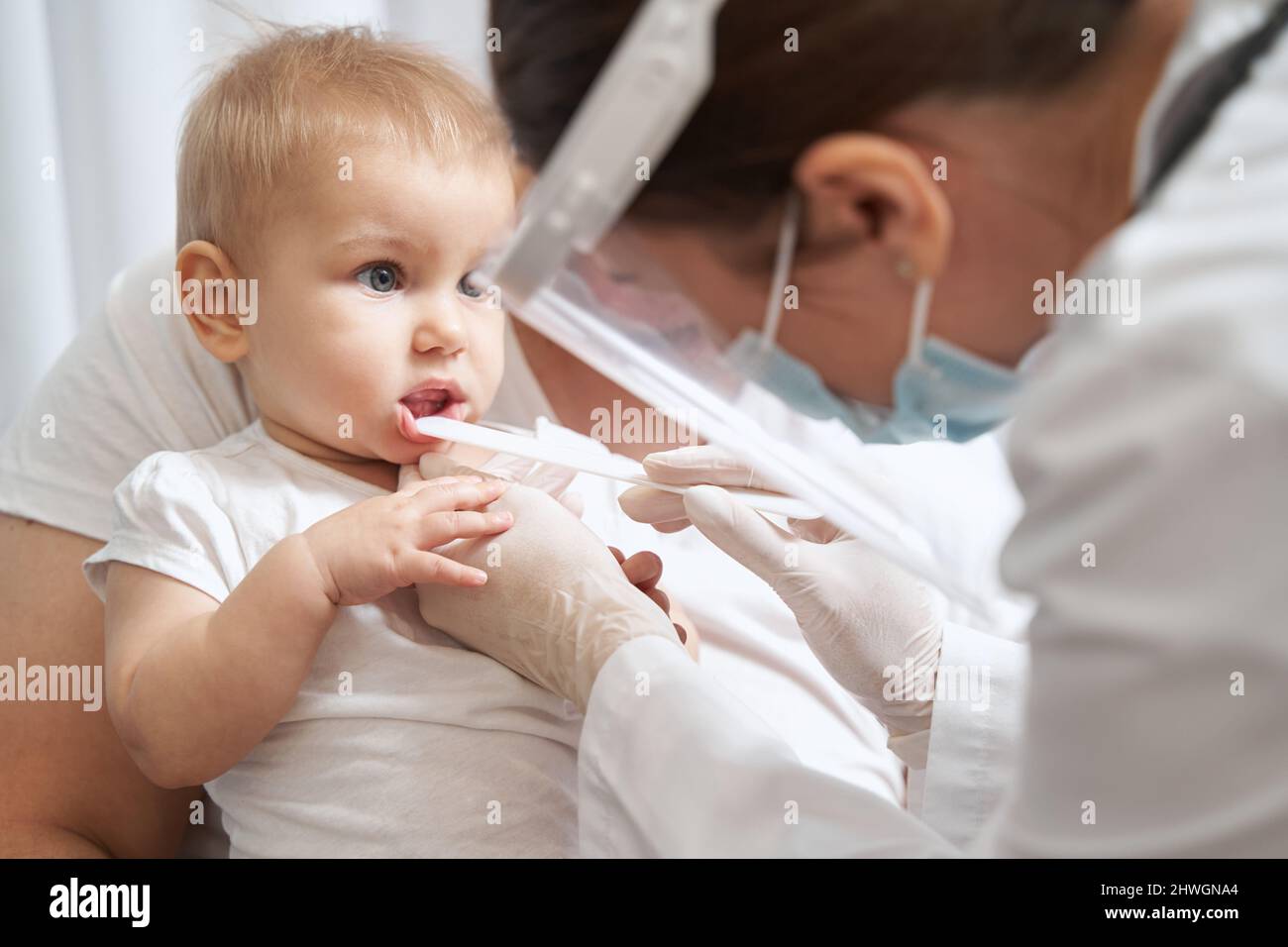 Medical therapist opening baby mouth with tongue depressor Stock Photo