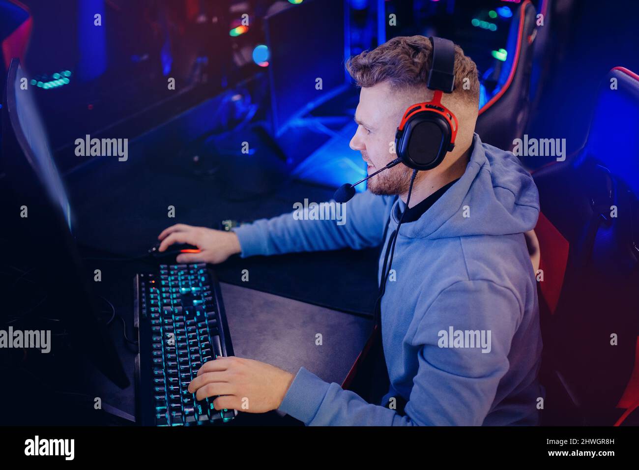 Streamer Young man plays computer games in headphones, neon lights ...