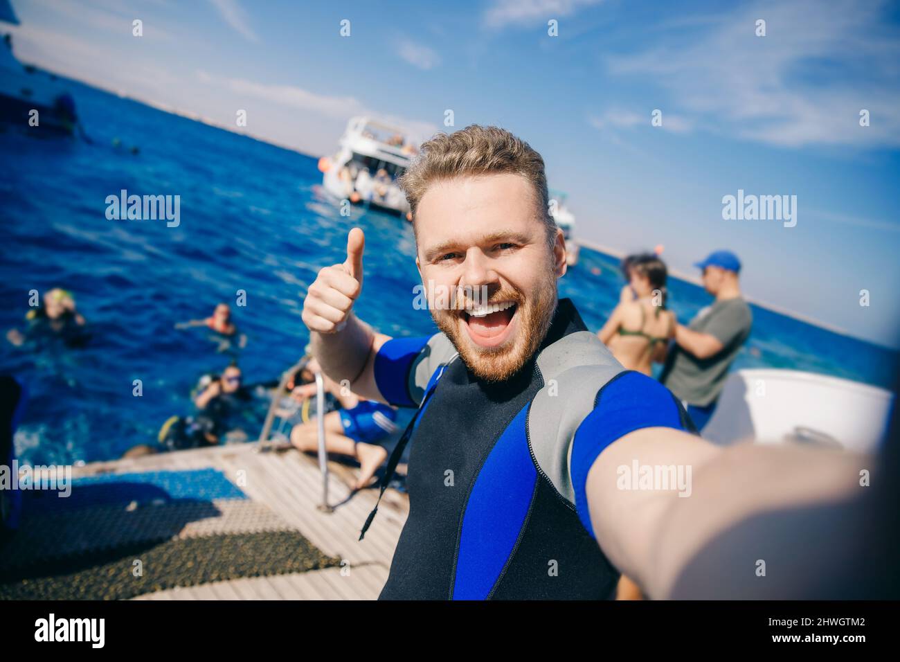 Selfie happy tourist man diver in wetsuit is preparing to dive into sea