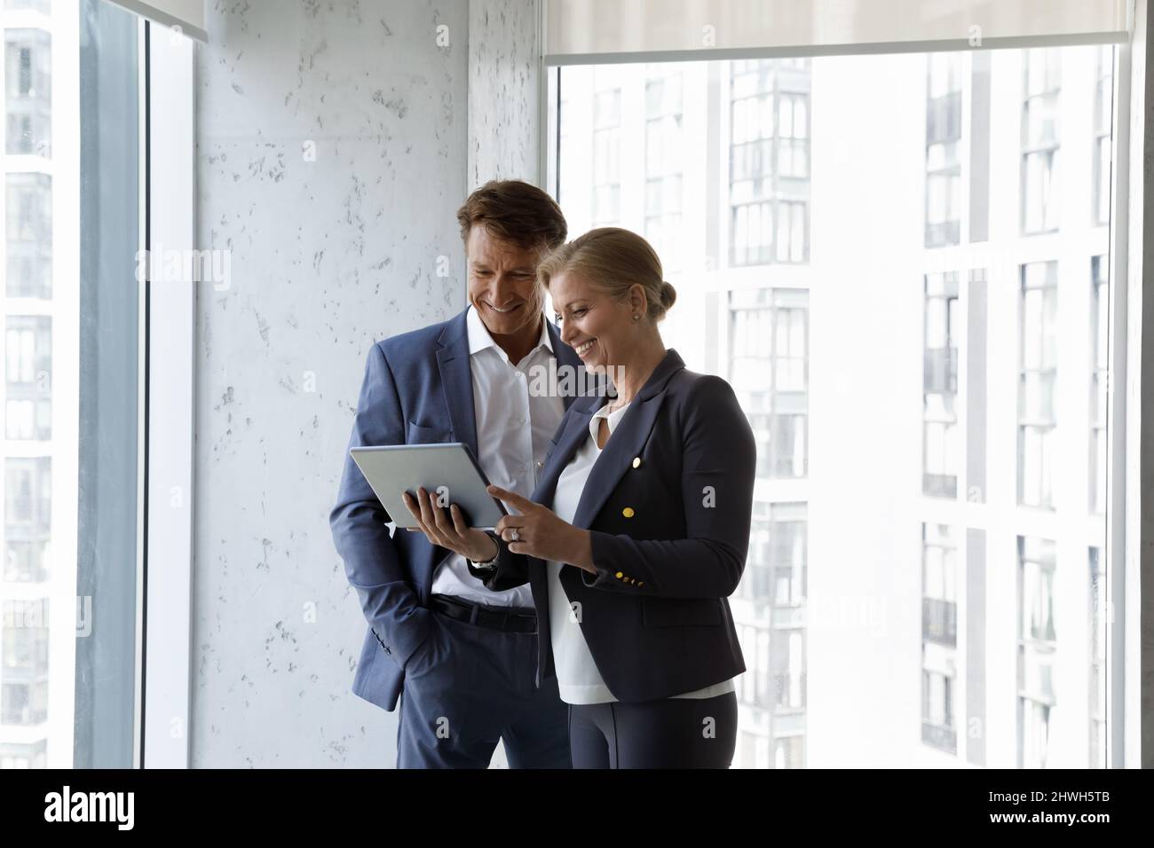 Happy middle aged colleagues using digital tablet. Stock Photo
