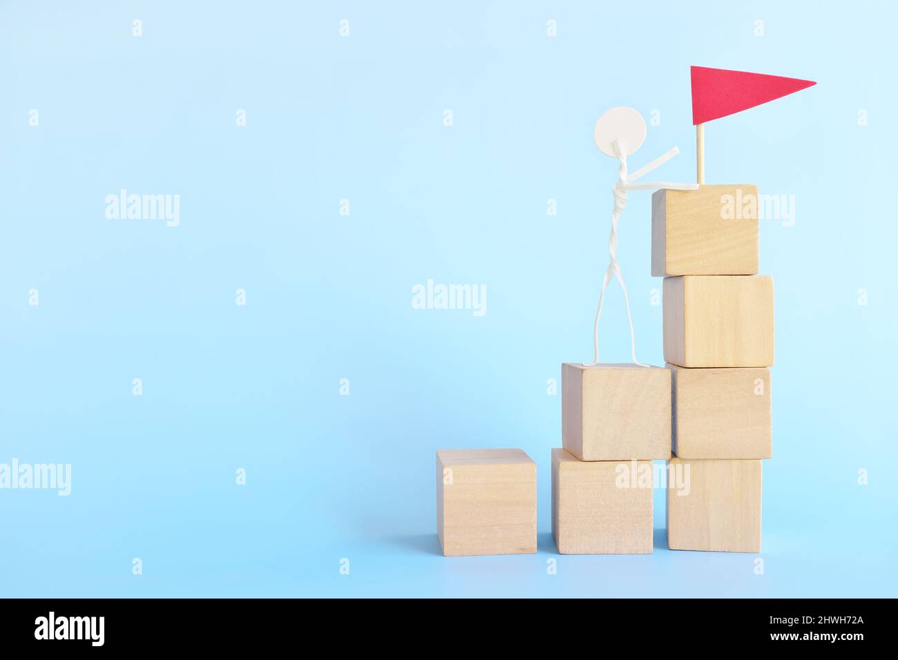 Ladder to success concept. Stick man climbing stairs with a red flag. Stock Photo