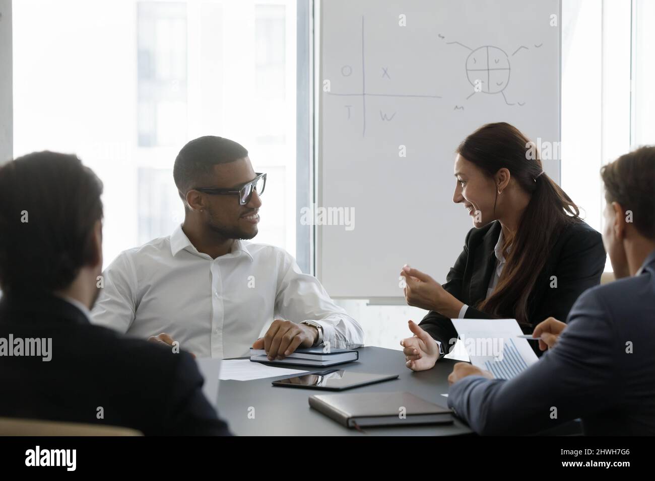 Happy young diverse colleagues discussing working issues in office. Stock Photo