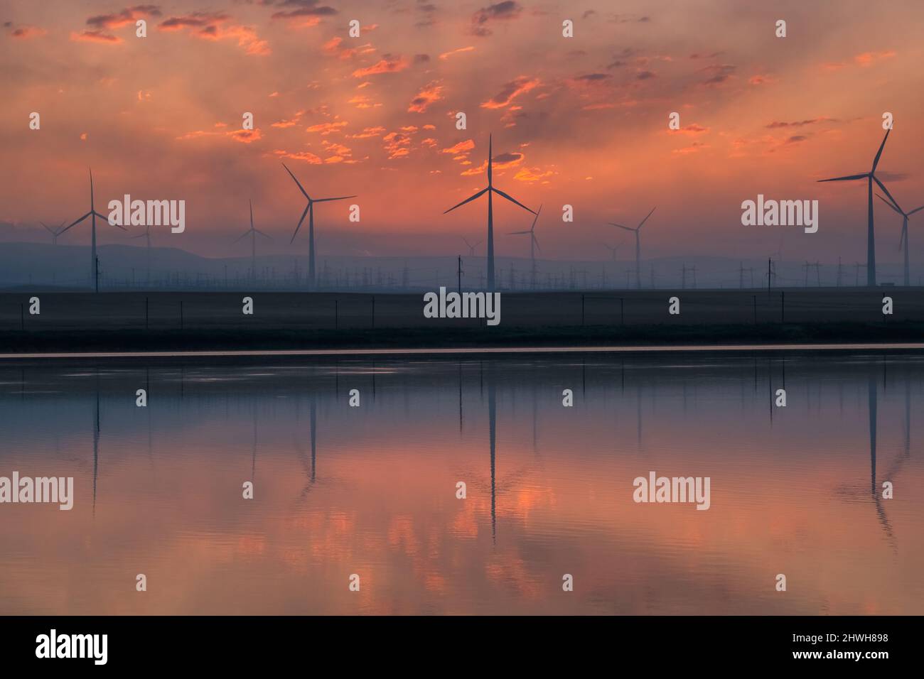 Windmill turbines at sunrise with reflection Stock Photo