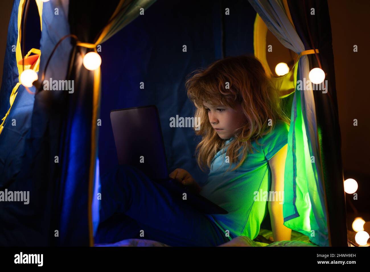 Little kid using laptop by night, child boy illuminated by the blue ...