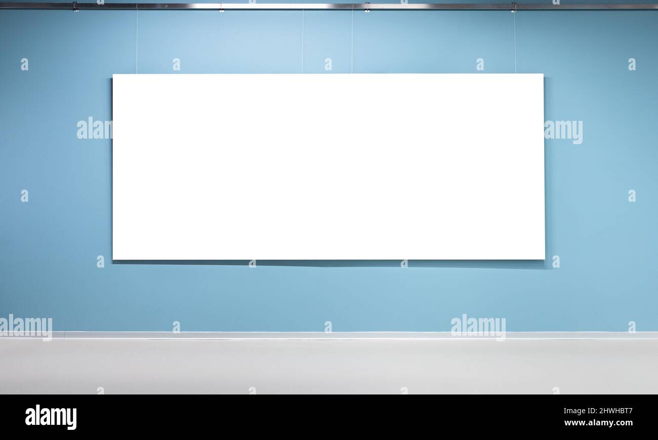 Blank white poster with copy space area is on blue wall in an exhibition hall. Empty interior, front view, background photo Stock Photo