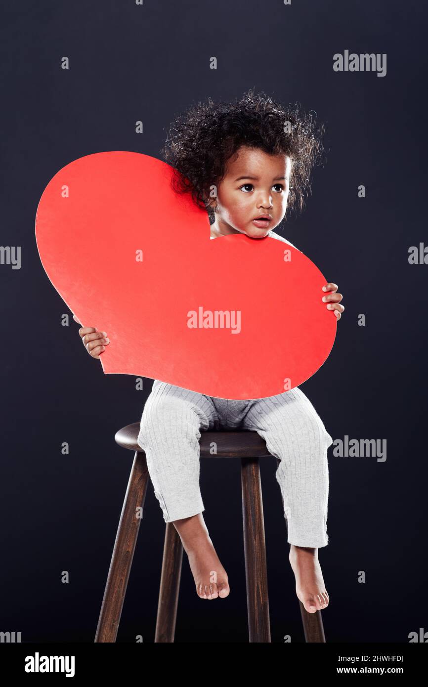 You have my heart. Studio shot of a cute little girl holding a big heart  isolated on black Stock Photo - Alamy