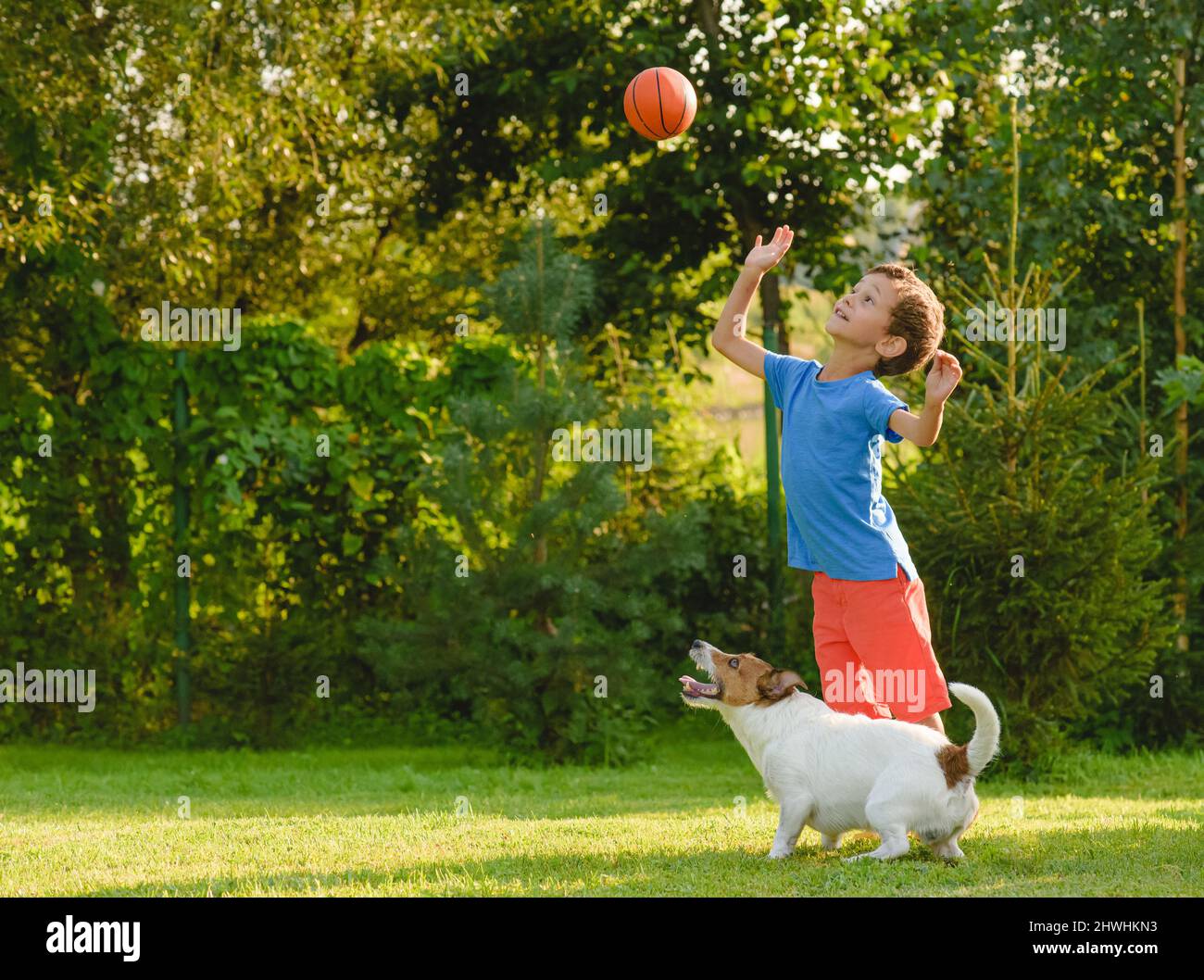 Kid and dog are playing leisure basketball game outdoors on summer day Stock Photo