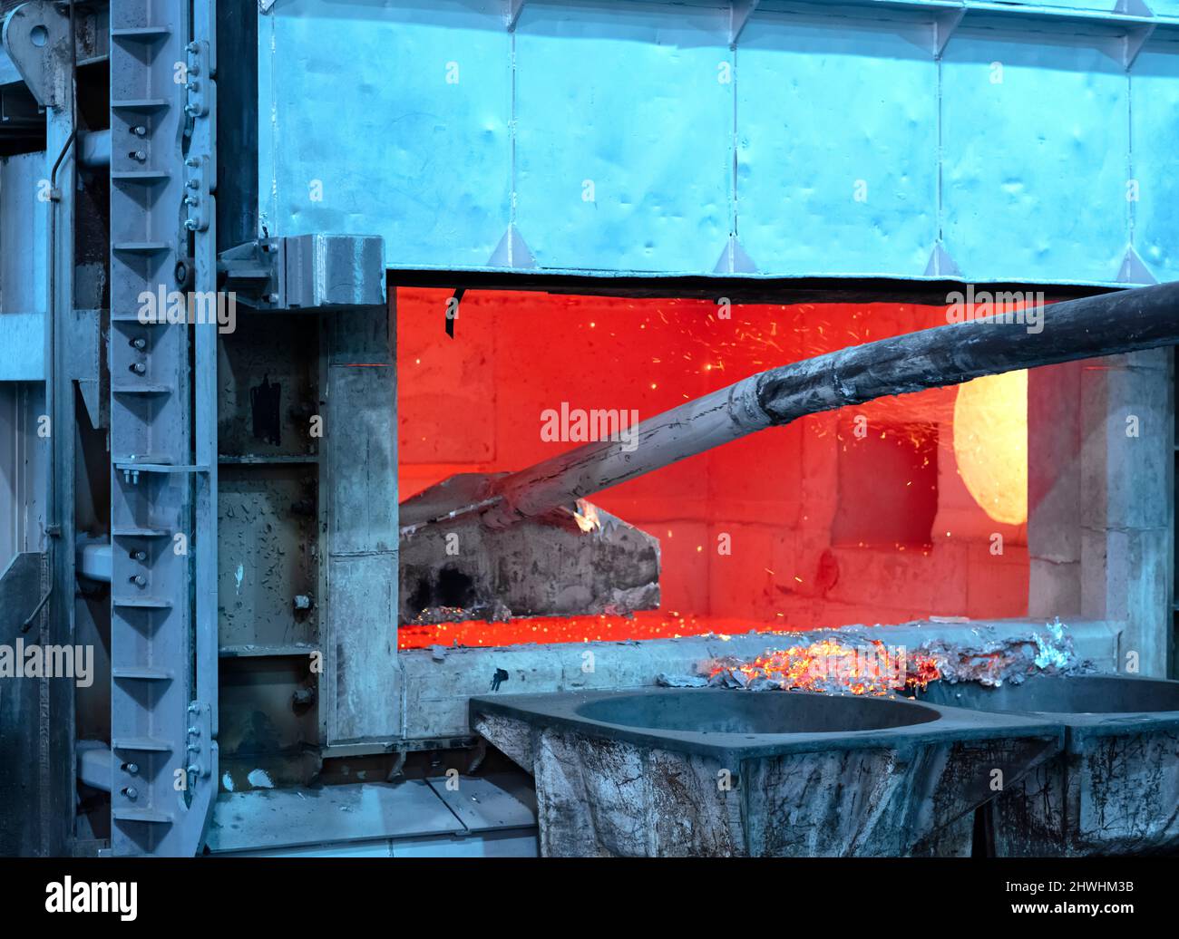 skimming melted aluminum for removing the dross before casting. Aluminum foundry works showing an open furnace Stock Photo