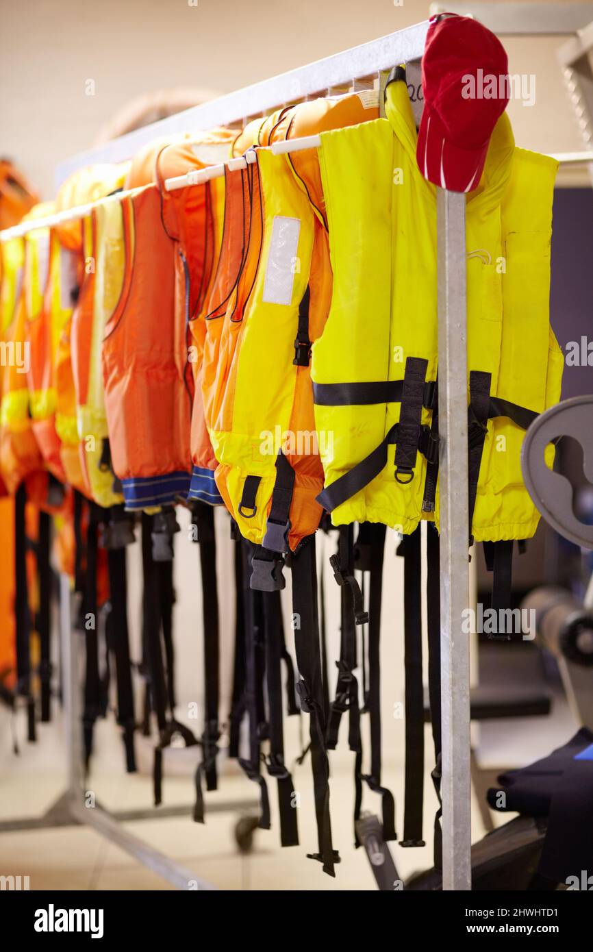 Ready when needed. Cropped shot of life jackets hanging on a rail inside a lifeguard station. Stock Photo