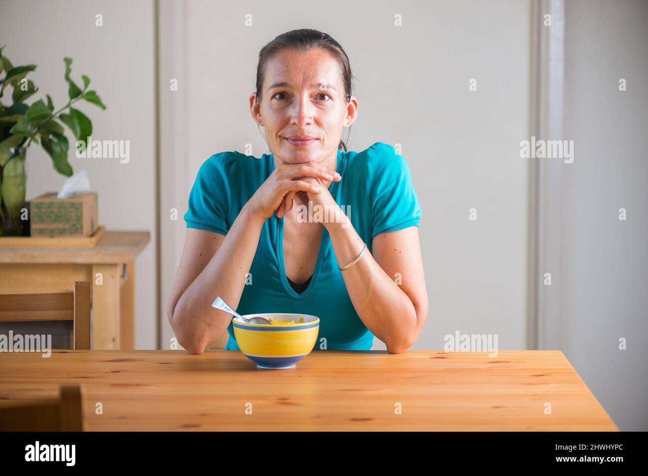 Smiling woman eating kitchari for a breakfast.  Stock Photo