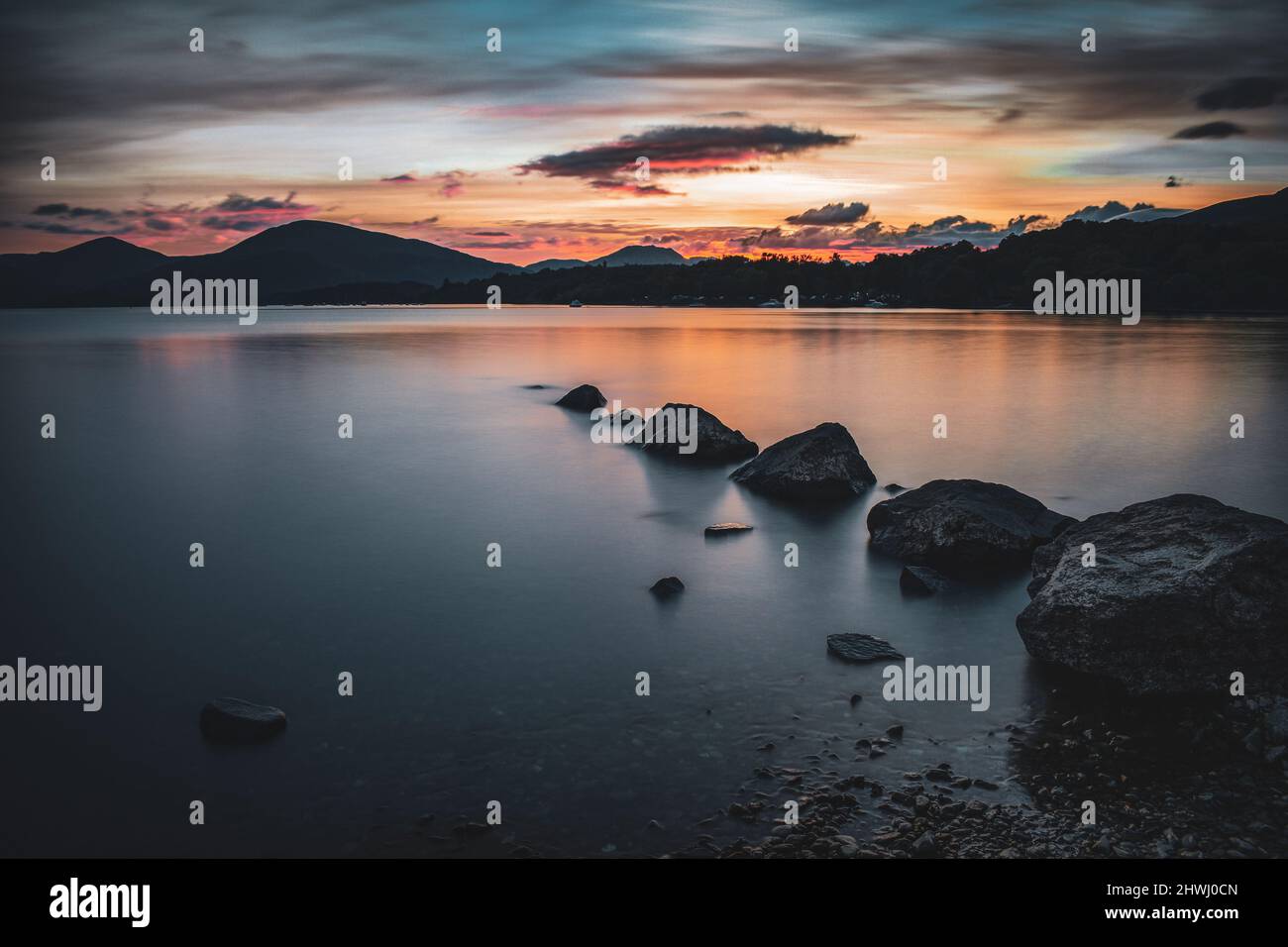 Peaceful Lake in Scotland with rocks by sunset Stock Photo