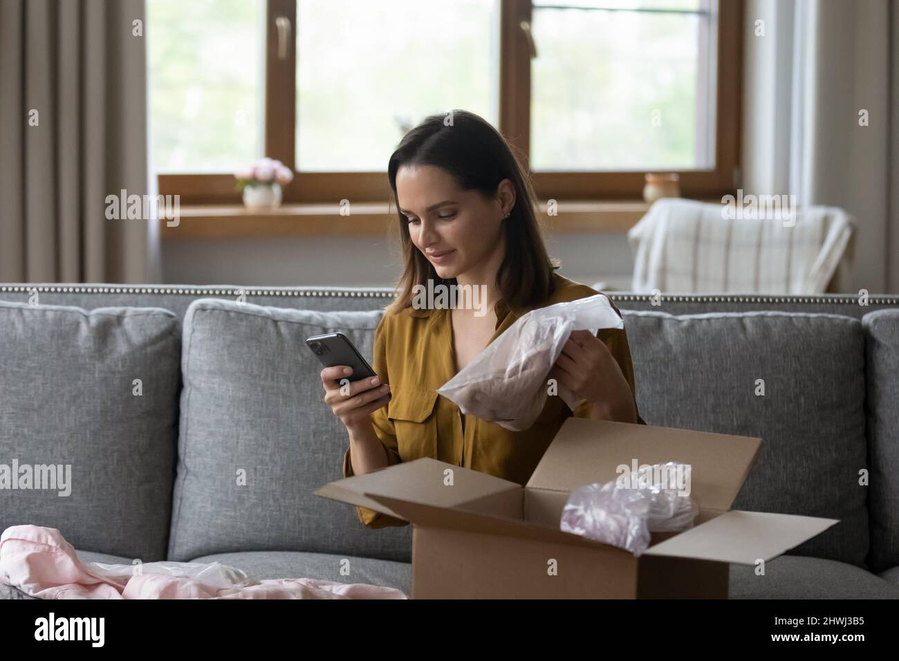 Woman holds smartphone check purchased clothes on ecommerce app webstore Stock Photo