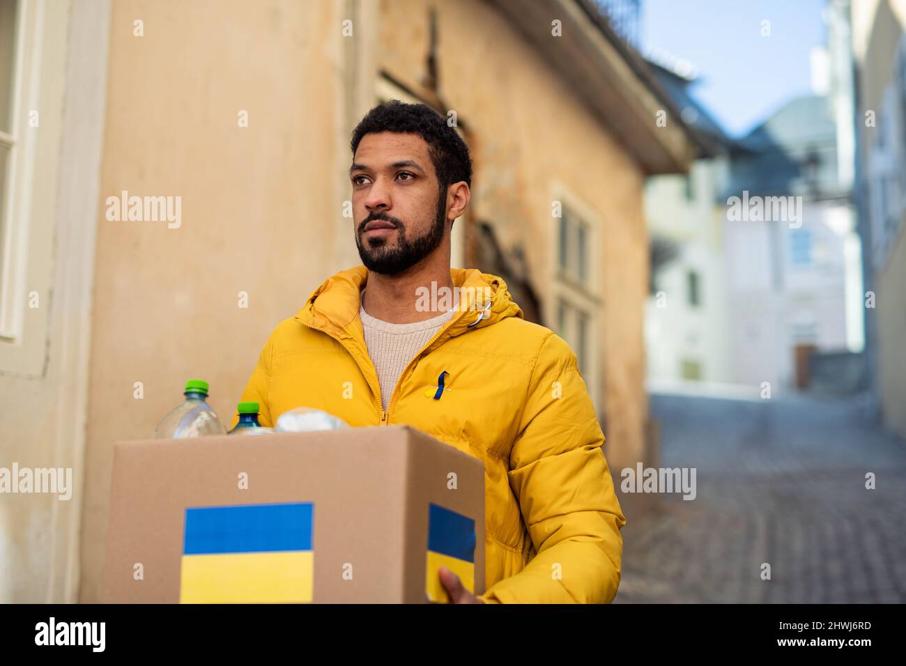 Volunteer cyrrying box with Humanitarian aid for Ukrainian refugees in street Stock Photo