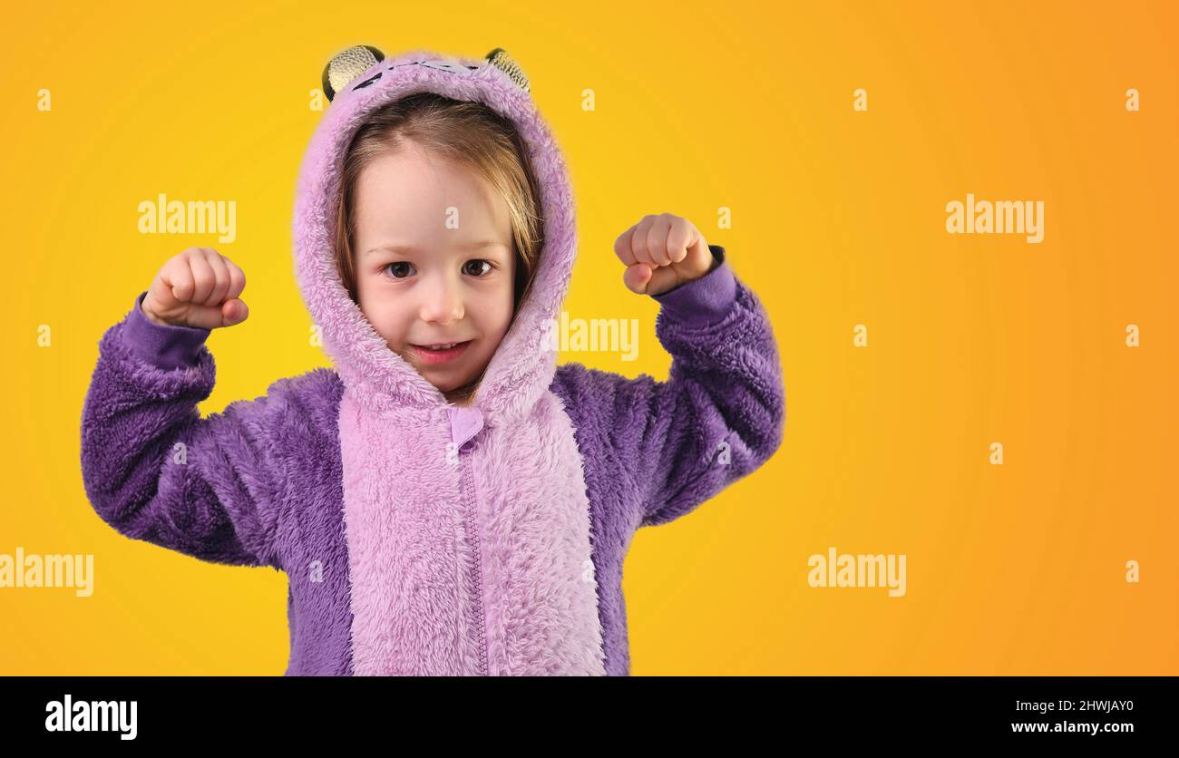 preschool child little shows strong strength tensing muscles in purple pajamas Stock Photo