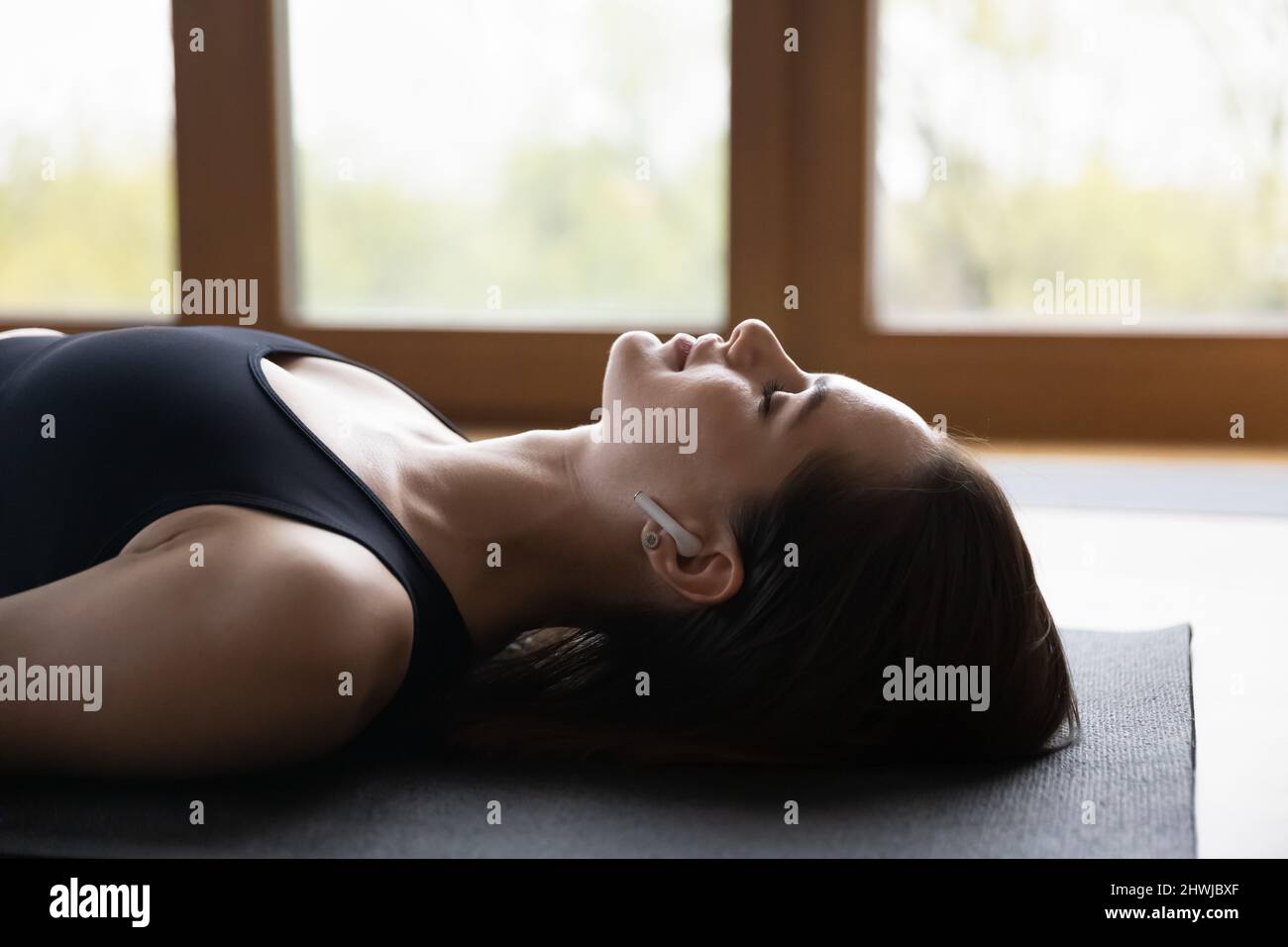 Side view young peaceful woman listen music meditating lying indoor Stock Photo