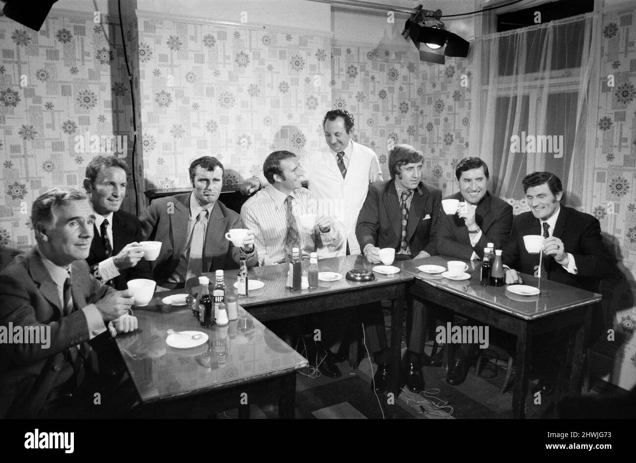 Seven former West Ham United footballers who are currently famous managers and coaches, get together over tea to talk about the old days. The tea party took place in Phil Cassetari's cafe near the Hammer's home ground, Upton Park.Pictured left to right are: Jimmy Adams (now Luton coach), Dave Sexton (manager of Chelsea), Noel Cantwell (manager of Coventry City), Malcolm Allison (Manchester City assistant manager), John Bond (Bournemouth manager), Frank O Farrell (Manchester United manager) and Malcolm Musgrove (Manchester United coach). Standing in the middle is cafe owner Phil Cassetaris, pro Stock Photo