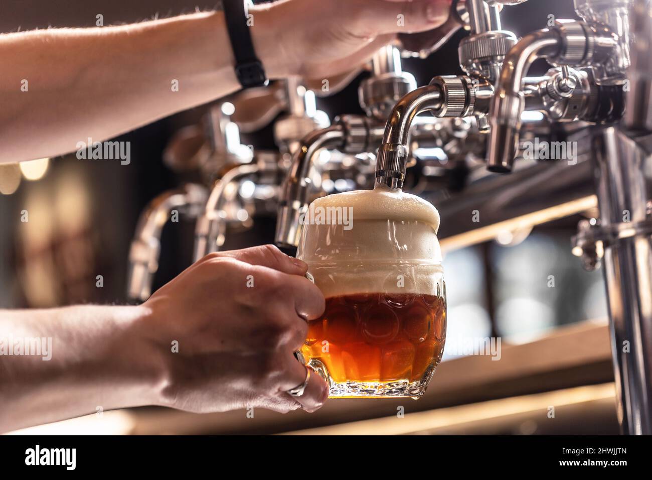 Tapping a half dark and half light beer into a mug by a bartender Stock