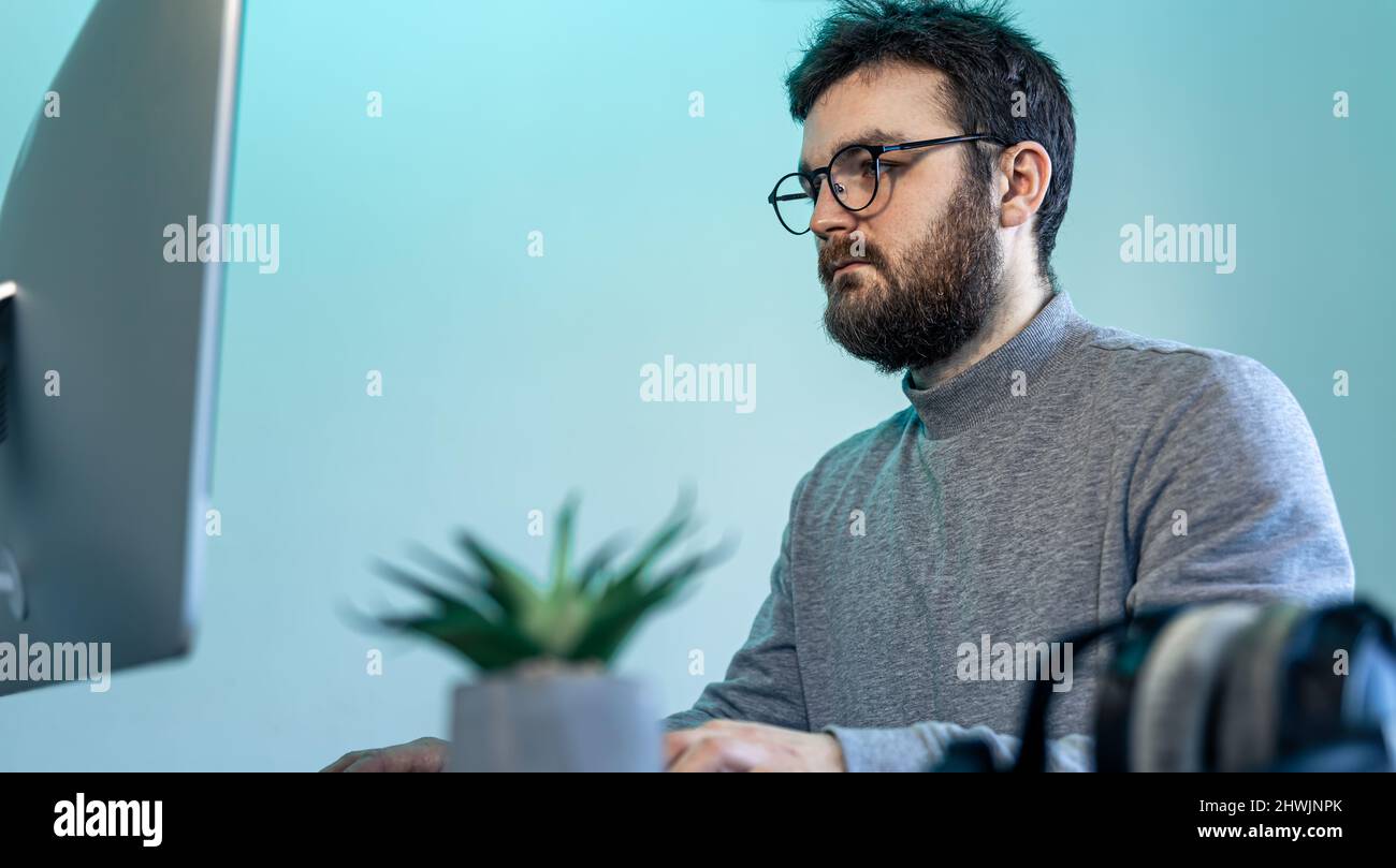 A man with glasses and a beard in front of a computer screen Stock