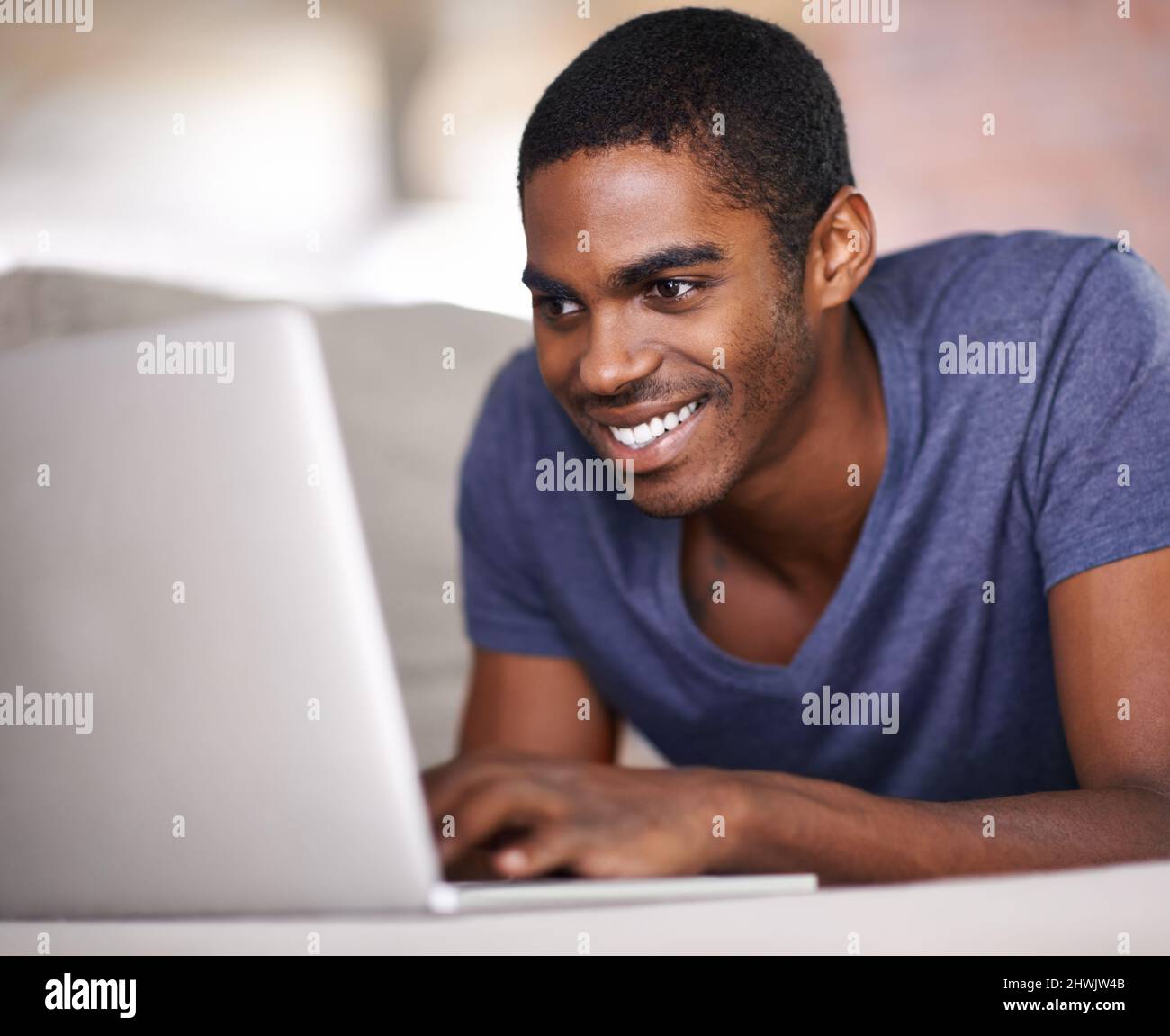 Chatting with someone special. Cropped shot of a handsome young man using his laptop while relaxing at home. Stock Photo