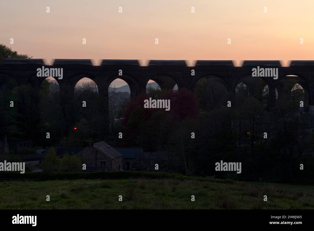 Silhouette of a Freight train of aggregates hoppers crossing chapel