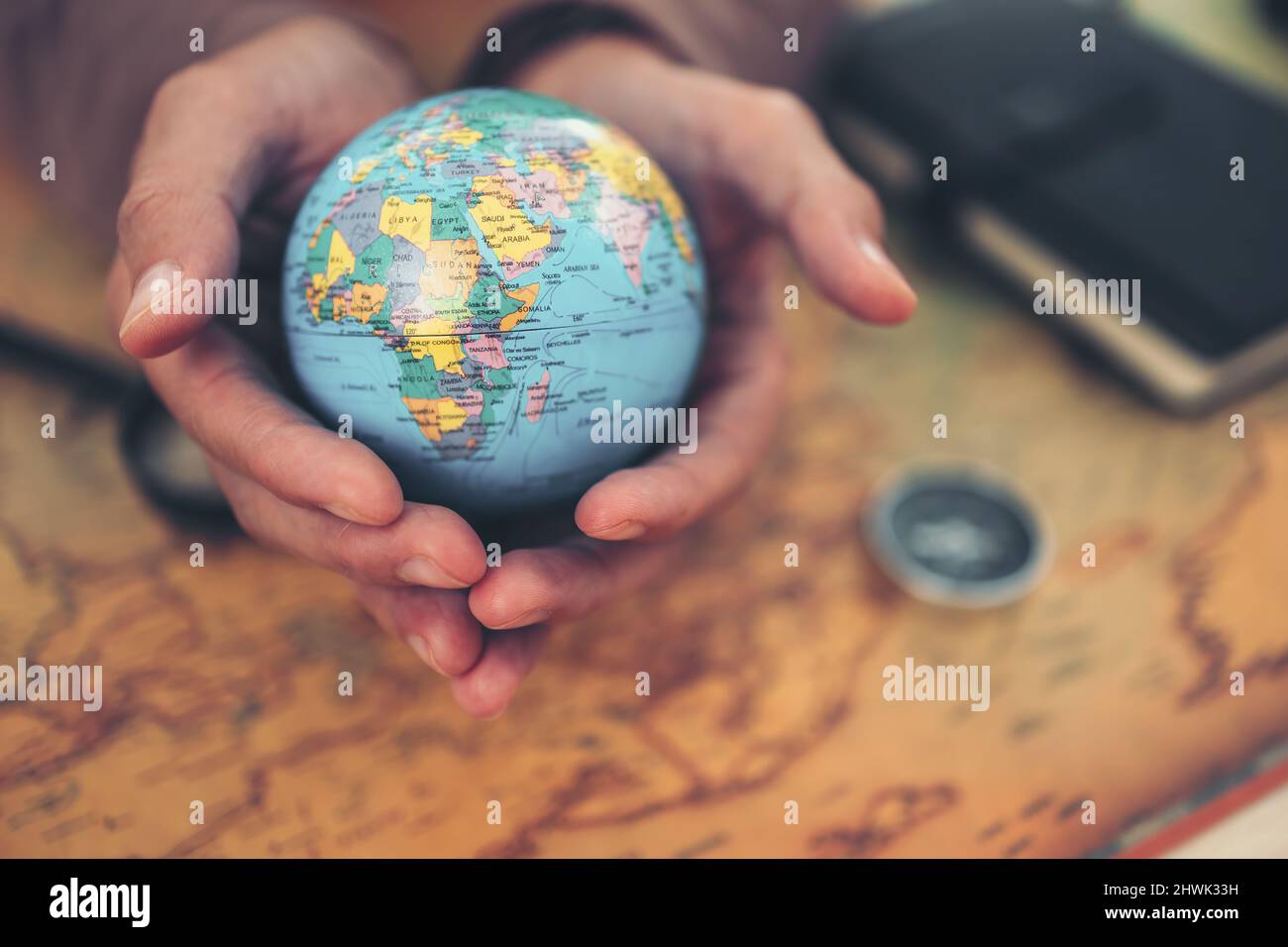 Globe, whole world in hands and compass, magnifying glass and book on route map on the table. Travel , Adventure and Discovery concept. Stock Photo