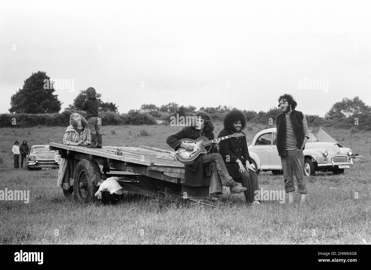 The Glastonbury Fayre of 1971, a free festival planned by Andrew Kerr and Arabella Churchill . Picture shows: Group of friends sitting on the back of a trailer playing guitar and singing songs at the festival. 19th June 1971. Stock Photo
