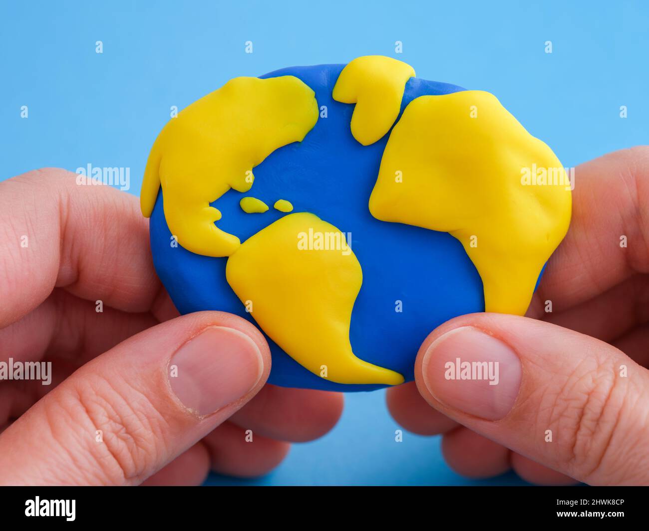 A woman holding the planet Earth in her hands. The planet Earth is made out of polymer clay. Stock Photo