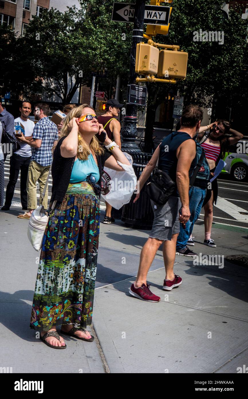 Woman wearing special glasses to view a partial eclipse of the sun in August 2017, New York City, United States Stock Photo