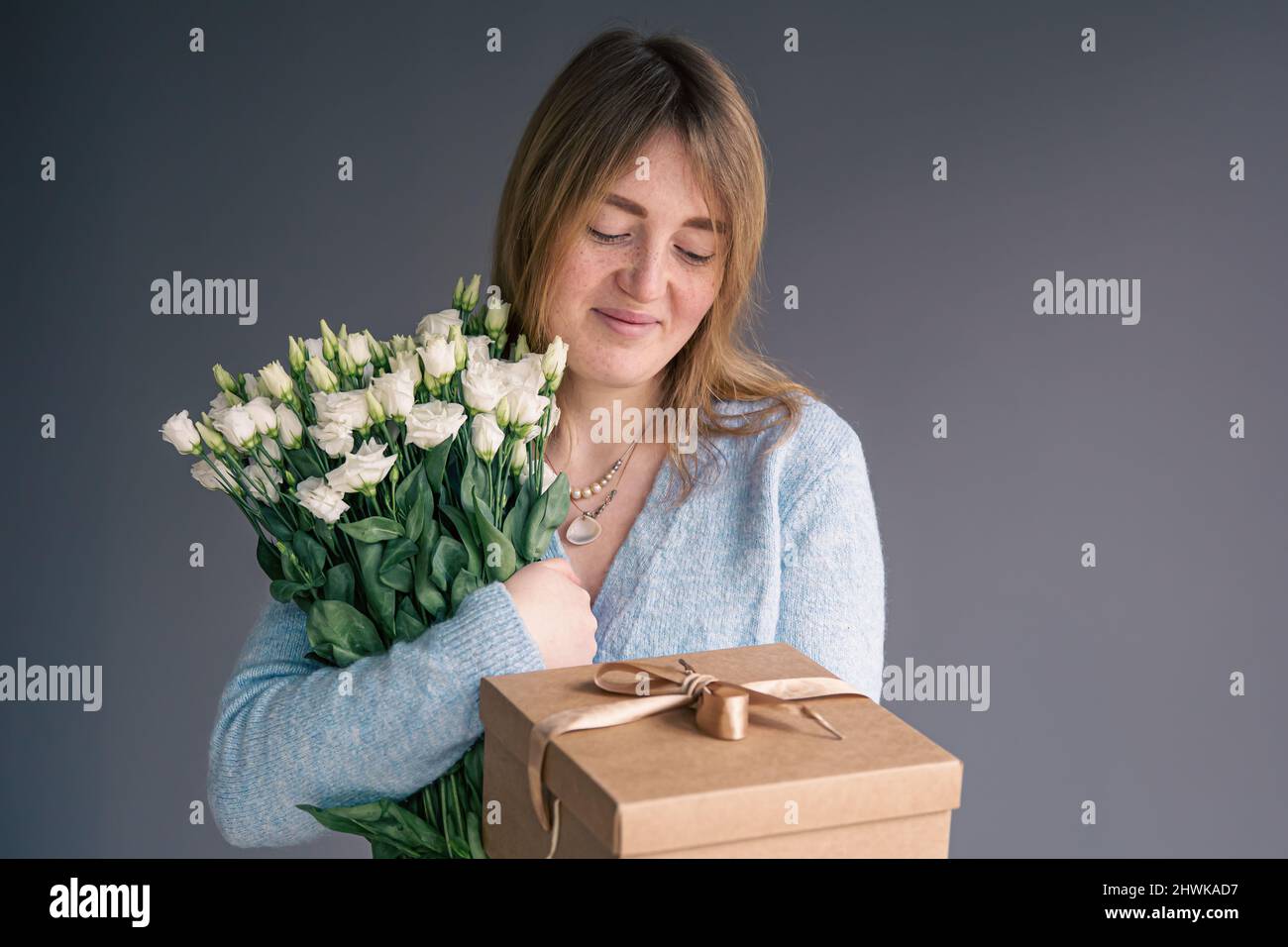 A young woman with a bouquet of roses unpacks a gift box Stock Photo ...