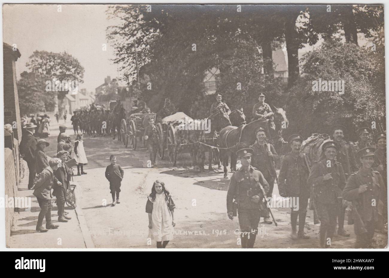 Royal Engineers at Southwell, Nottinghamshire, 1915: photograph of a column of soldiers marching through the town street in full uniform with rifles, several horse drawn carts with drivers are also included. Local men, women & children can be seen watching the event & a girl & boy appearing to be marching with the soldiers Stock Photo