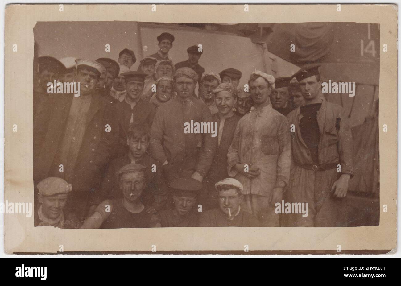 Group photograph of Royal Navy stokers in the early 20th century (First World War period). Many of the men are smoking cigarettes, their clothes and faces are marked with soot, and they are wearing a range of headwear - army and navy style caps, flat caps and knotted handkerchiefs Stock Photo